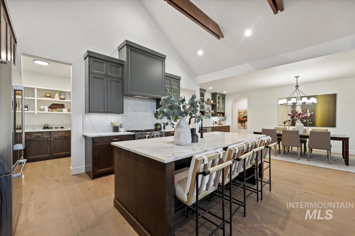 Kitchen with decorative backsplash, light wood-style flooring, stainless steel appliances, a breakfast bar, and a center island
