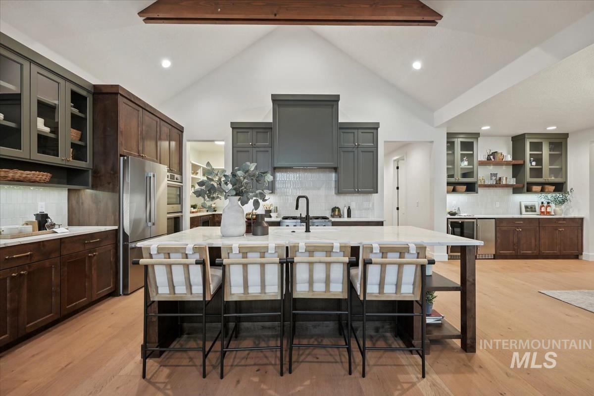 Kitchen with glass insert cabinets, open shelves, backsplash, appliances with stainless steel finishes, and light wood-style flooring