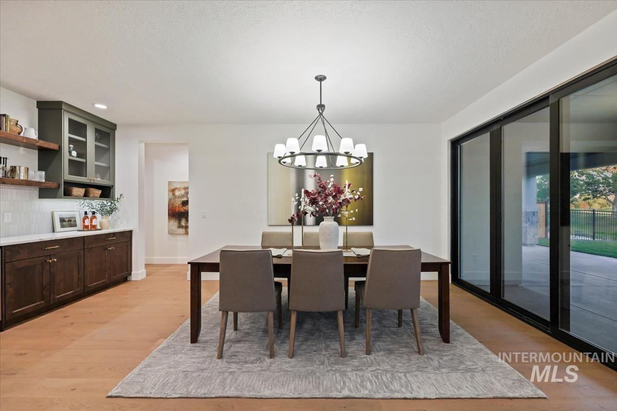 Dining area featuring light wood-type flooring, a chandelier, recessed lighting, and a textured ceiling