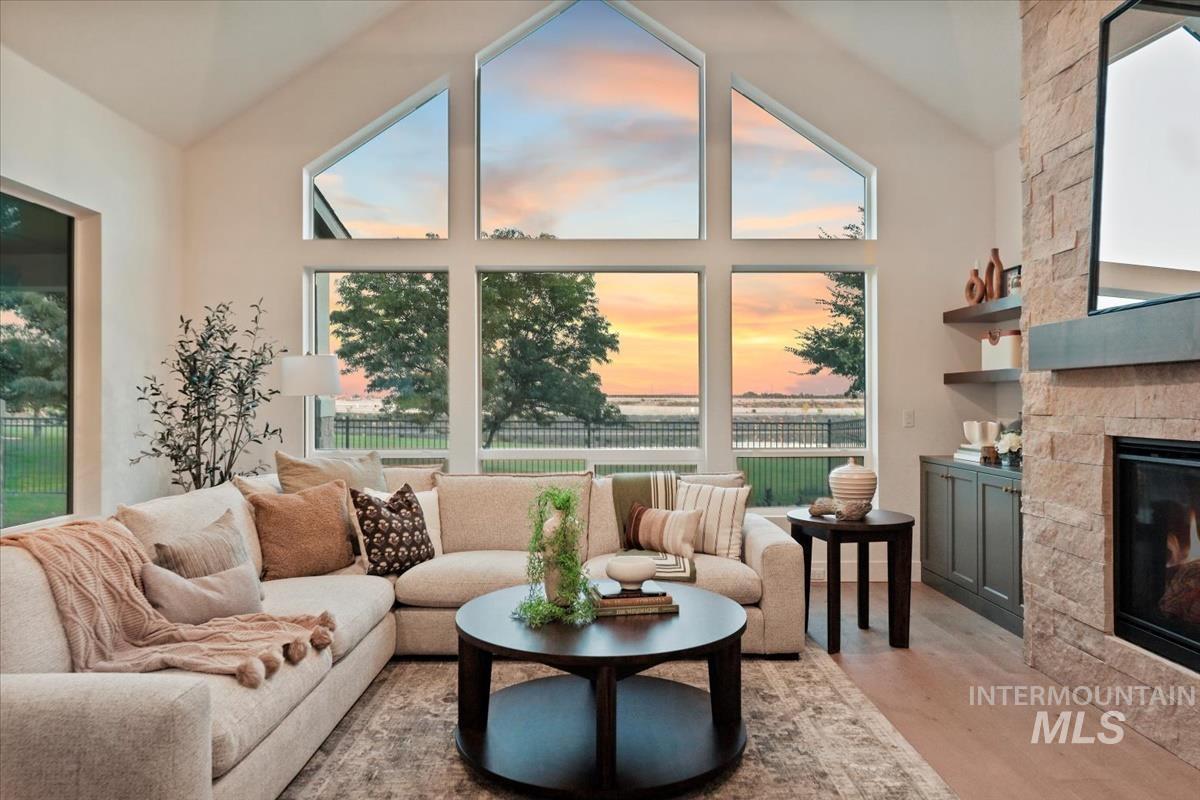 Living area featuring a fireplace, healthy amount of natural light, wood finished floors, and high vaulted ceiling