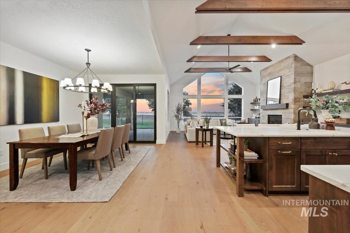 Dining area with beam ceiling, light wood-type flooring, a chandelier, and high vaulted ceiling