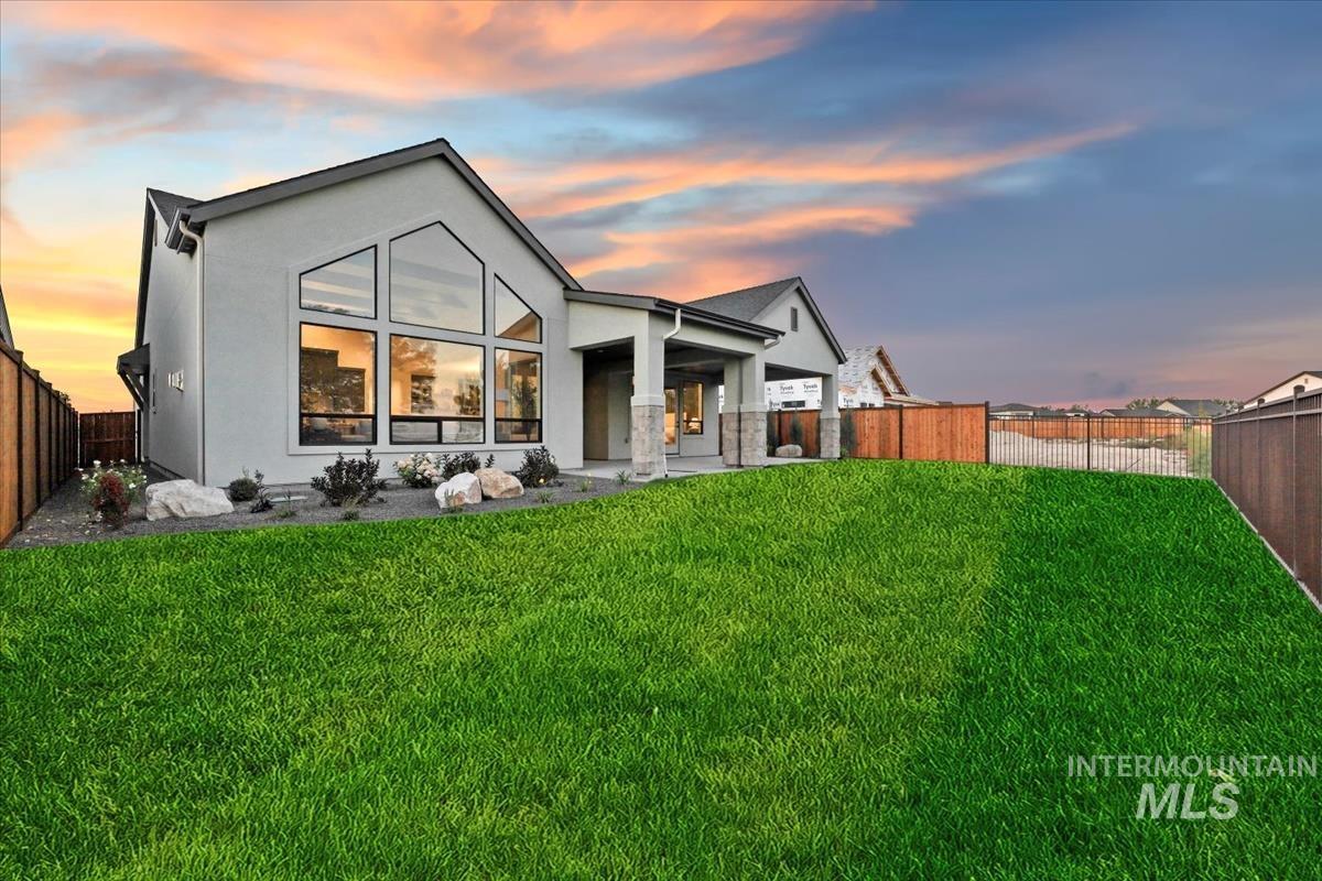 Rear view of house with a fenced backyard, a patio, stucco siding, and stone siding