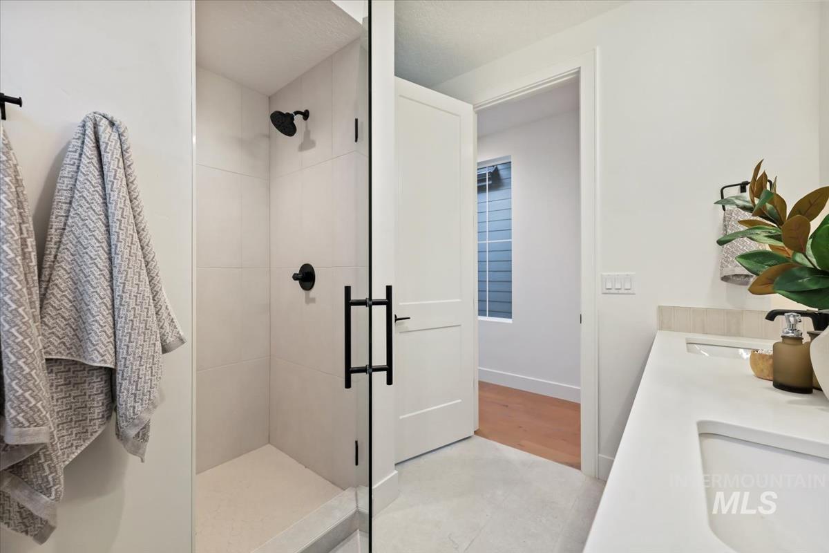 Bathroom with a stall shower, double vanity, and light tile patterned floors