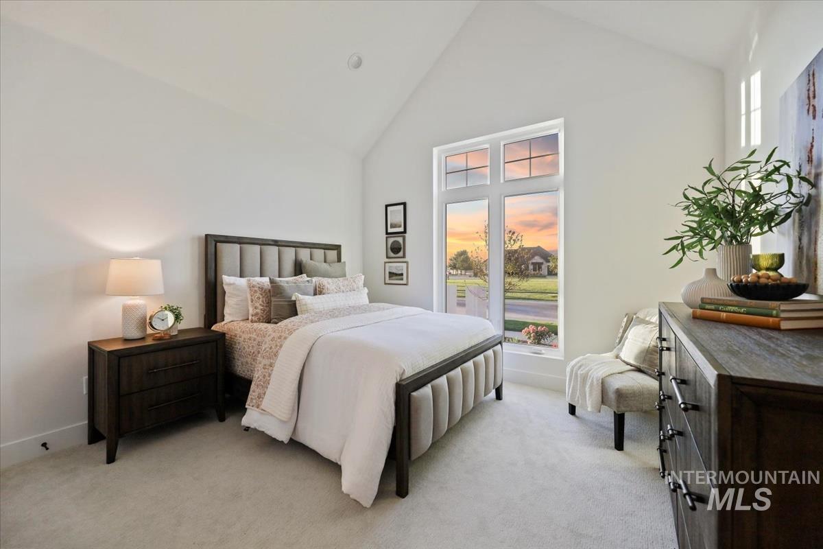 Bedroom with high vaulted ceiling and light colored carpet