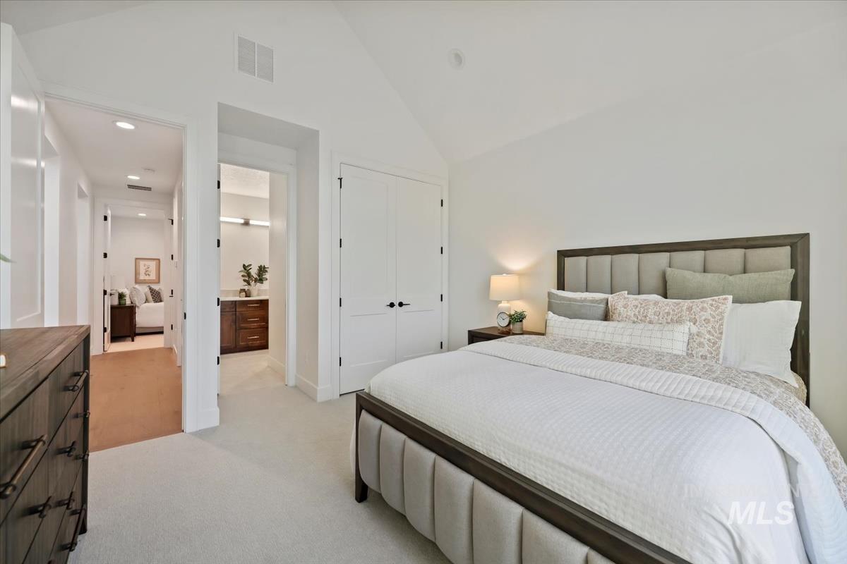 Bedroom featuring light colored carpet, a closet, recessed lighting, high vaulted ceiling, and connected bathroom
