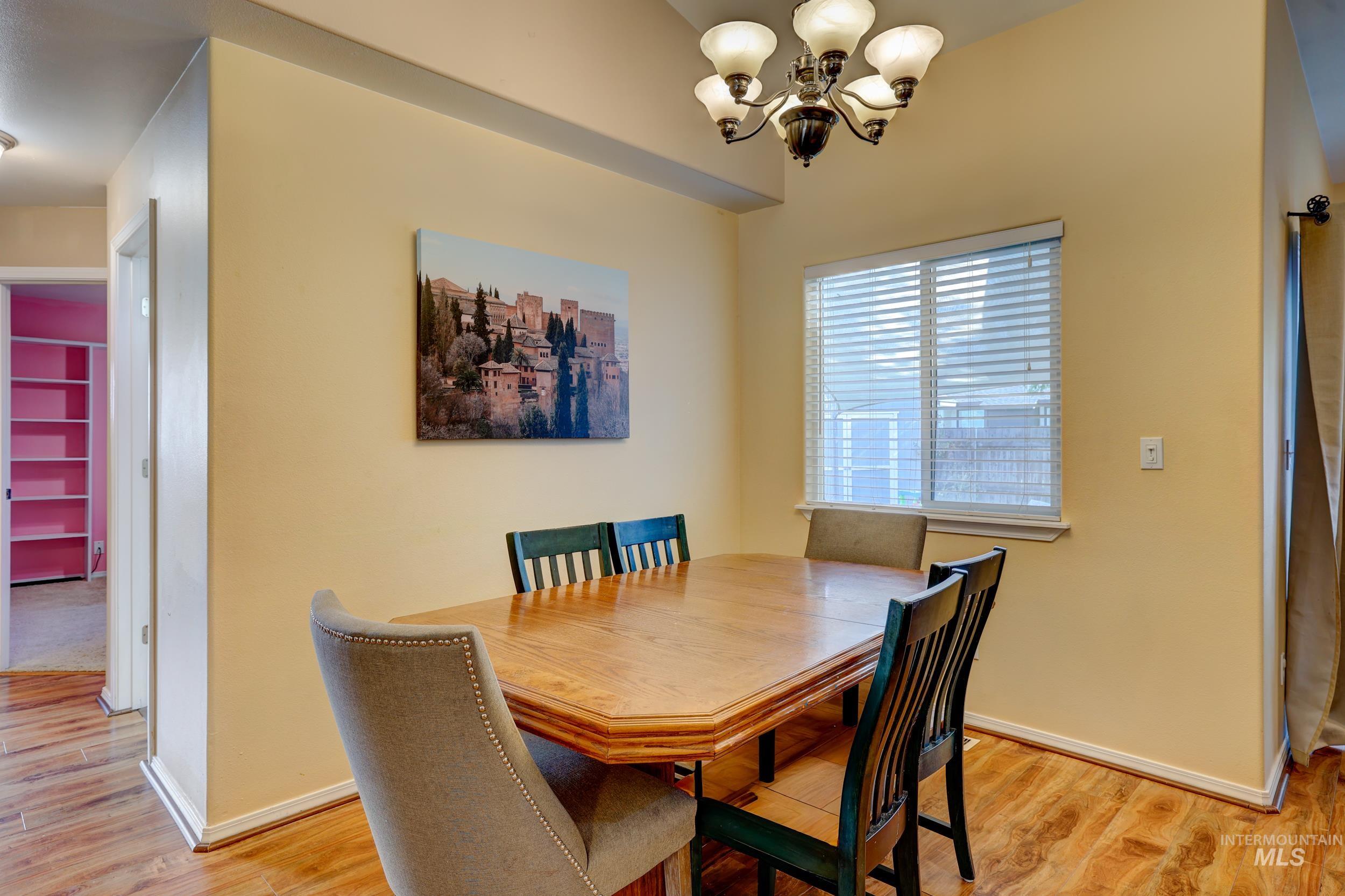 Dining room with light wood-type flooring and a chandelier