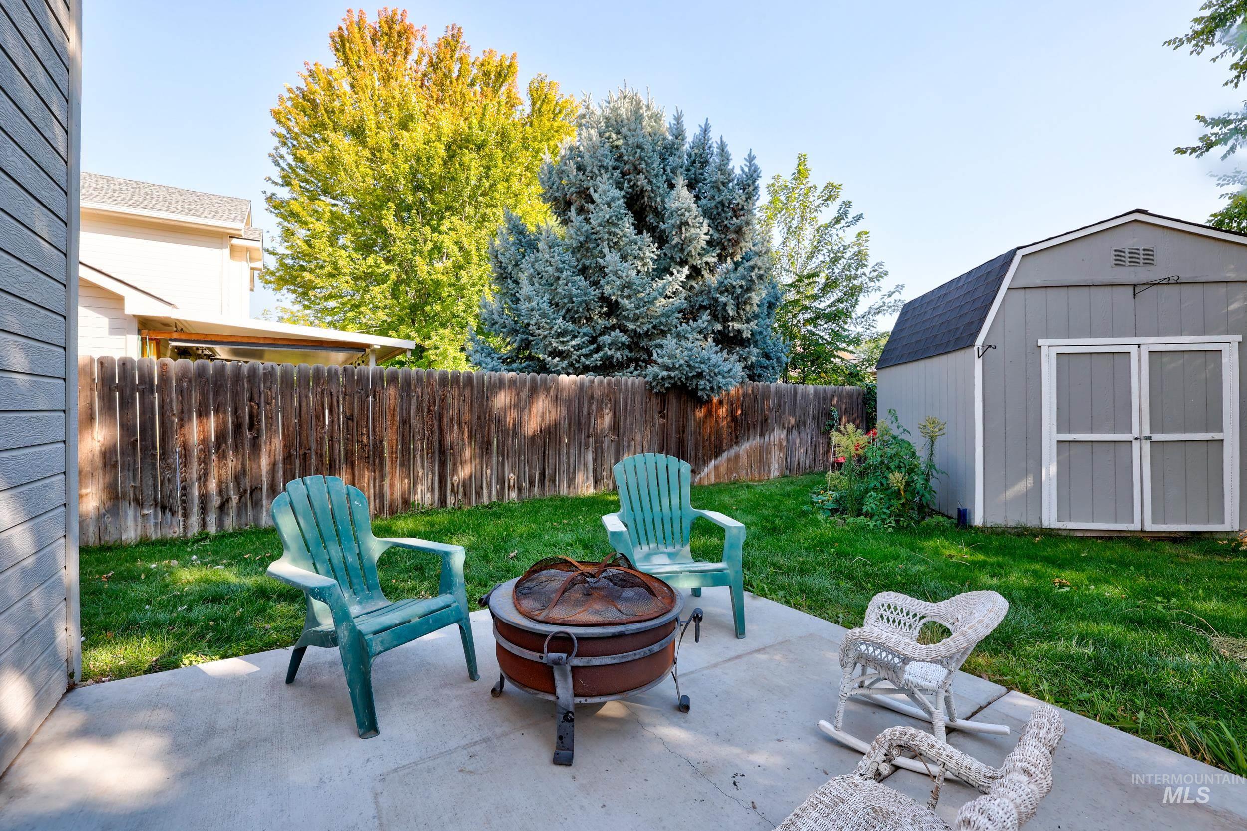 Fenced backyard featuring a shed, a fire pit, and a patio area