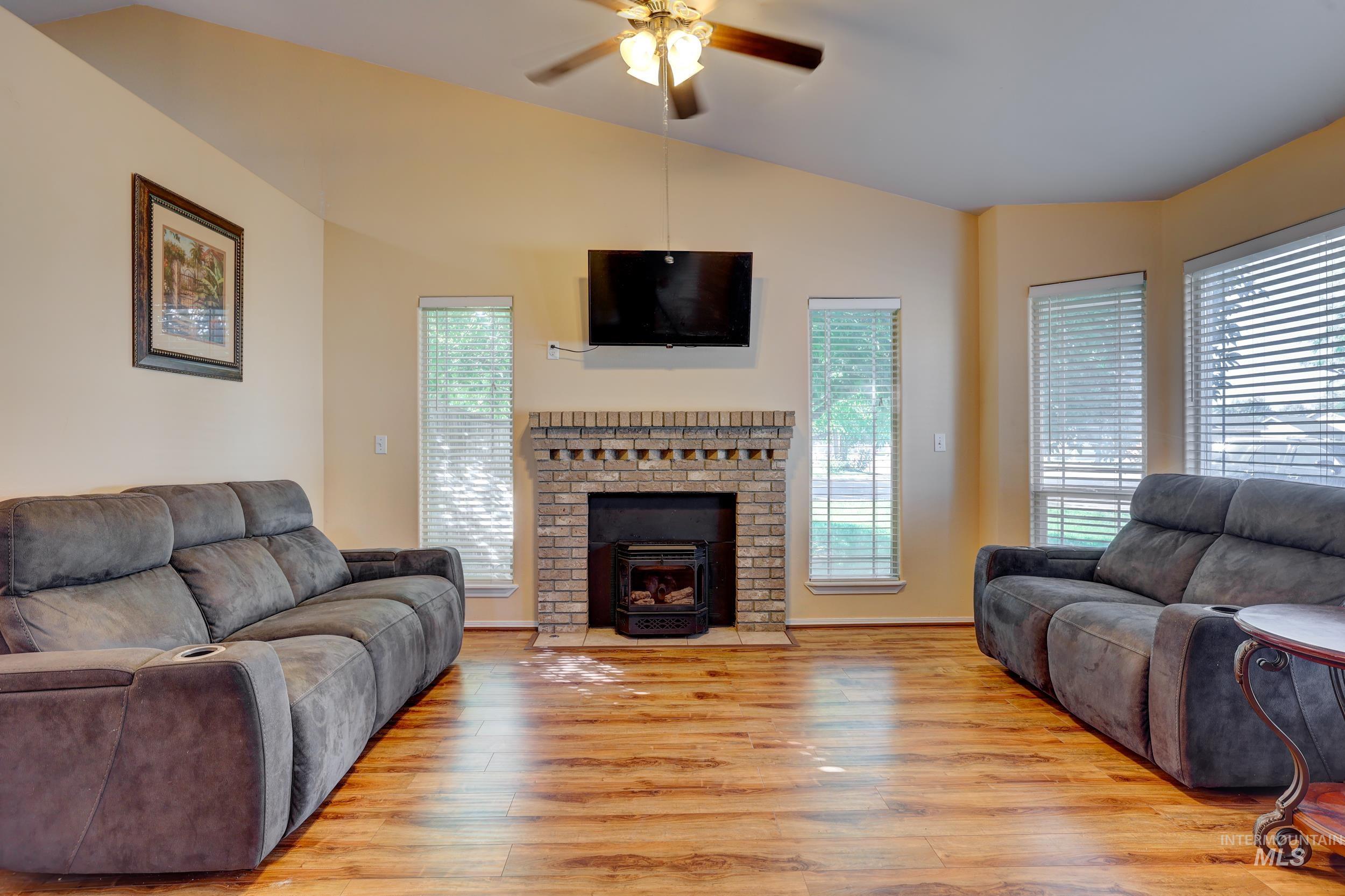 Living area with lofted ceiling, light wood-style flooring, and a ceiling fan