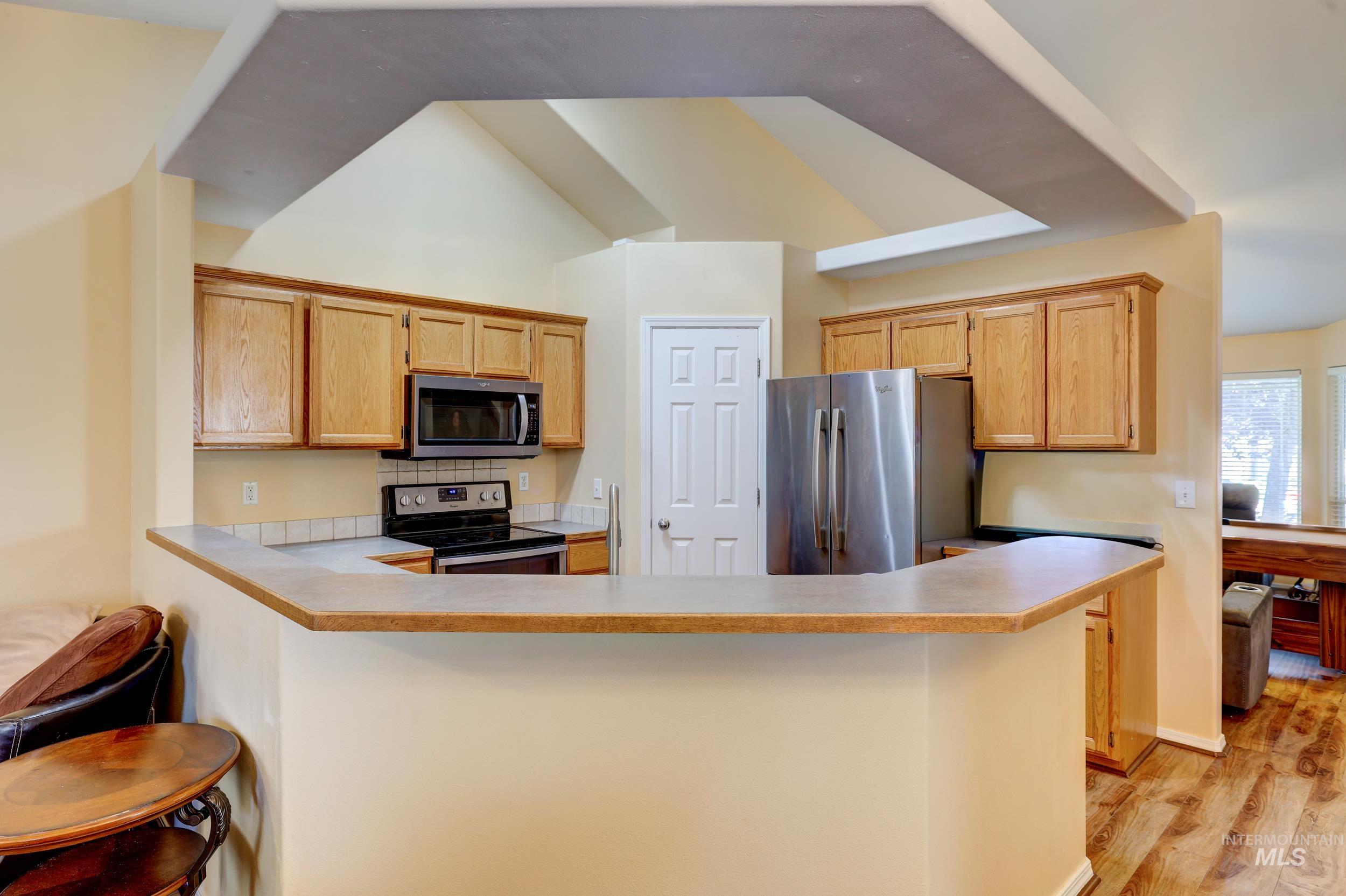 Kitchen featuring a breakfast bar area, appliances with stainless steel finishes, a peninsula, and light wood-style floors
