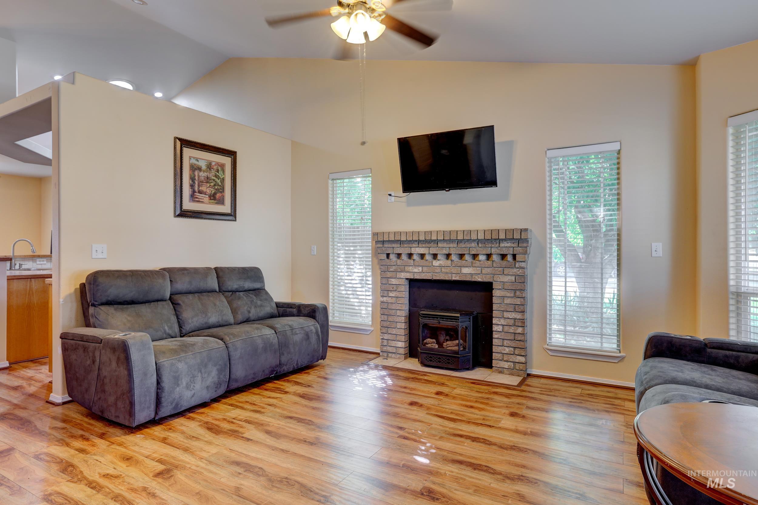Living room featuring vaulted ceiling, light wood finished floors, and ceiling fan