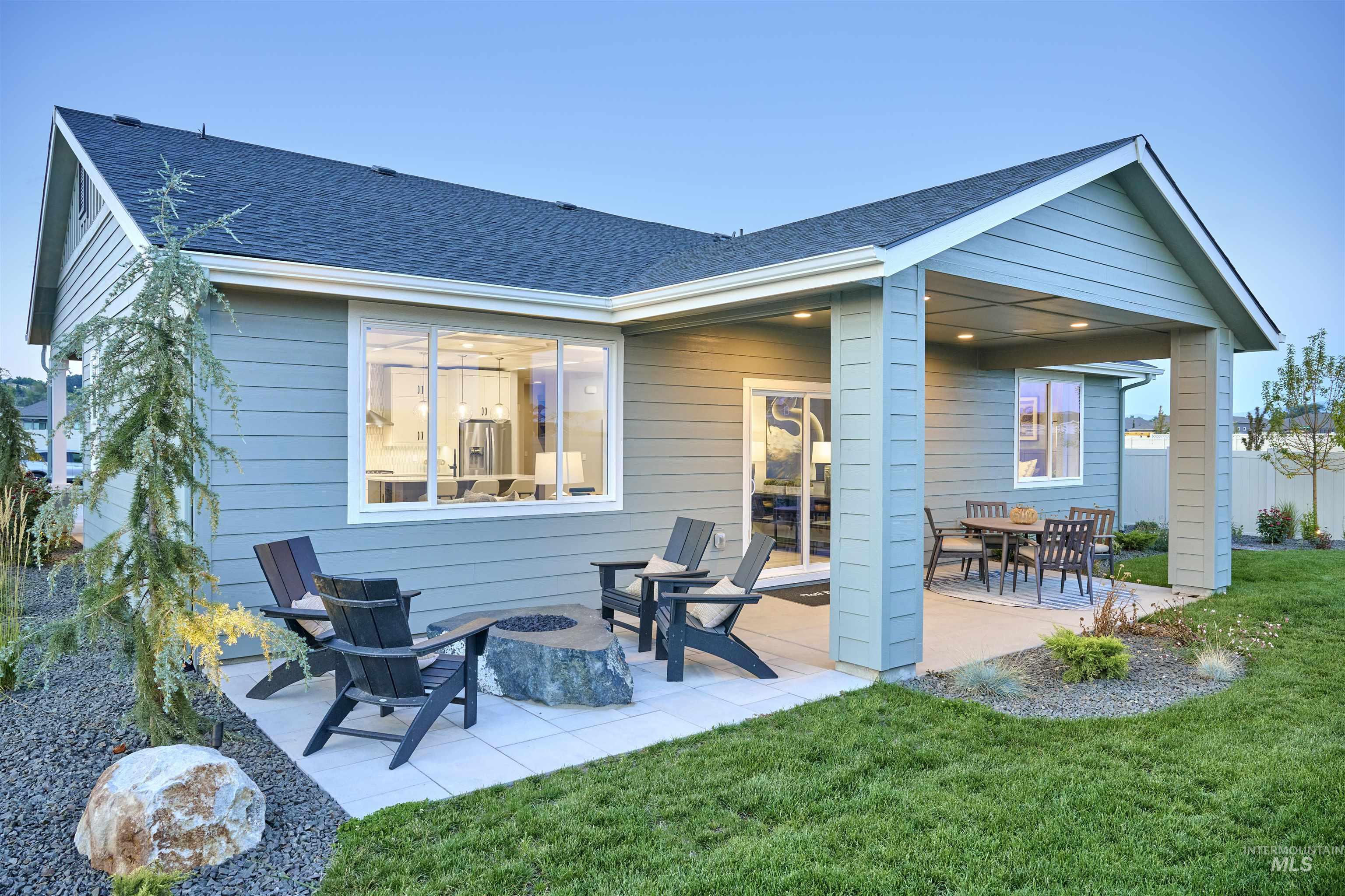 Back of property featuring a patio area, a lawn, roof with shingles, and a fire pit