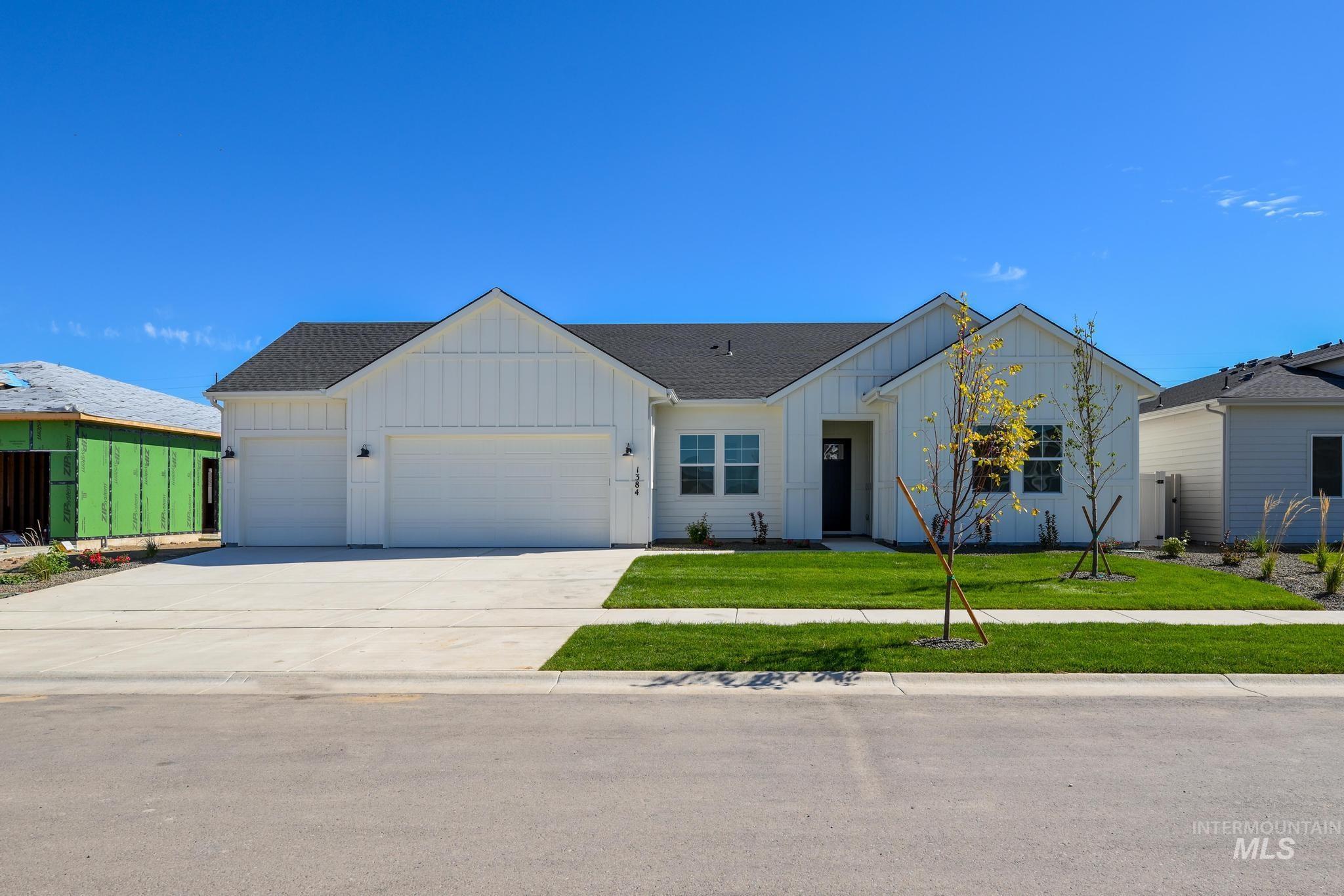 Modern farmhouse style home with board and batten siding, a garage, concrete driveway, and roof with shingles