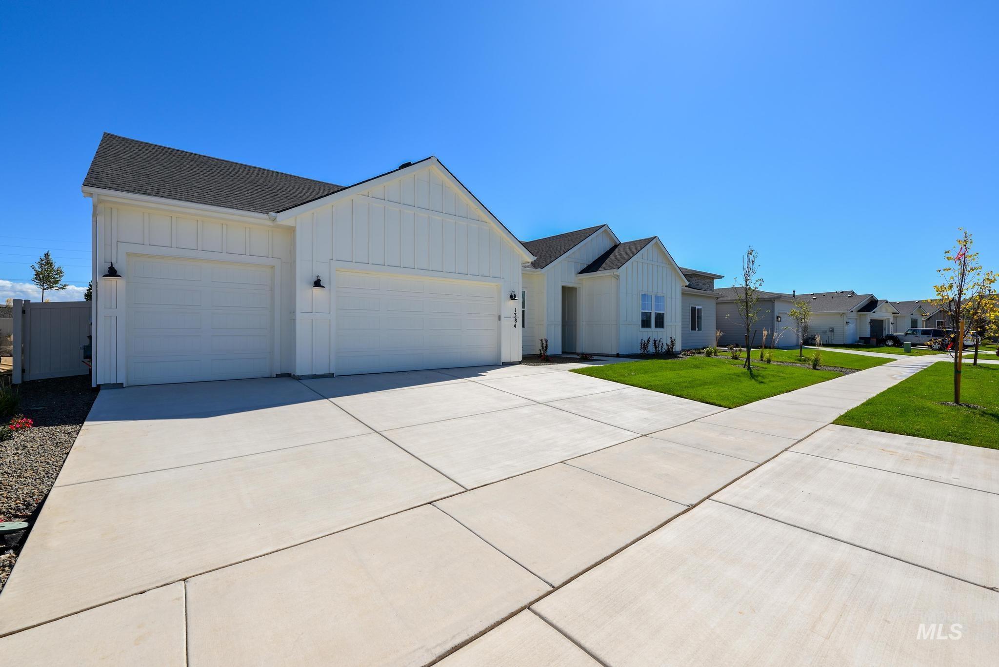 Modern farmhouse featuring board and batten siding, driveway, a garage, a front lawn, and a shingled roof