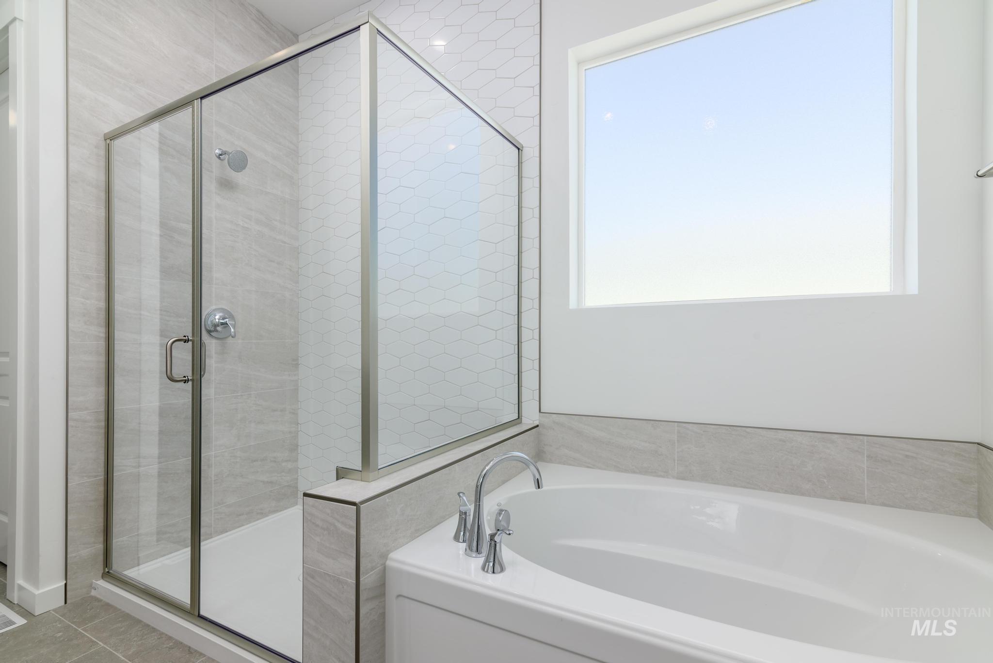 Bathroom featuring a bath, a stall shower, and plenty of natural light