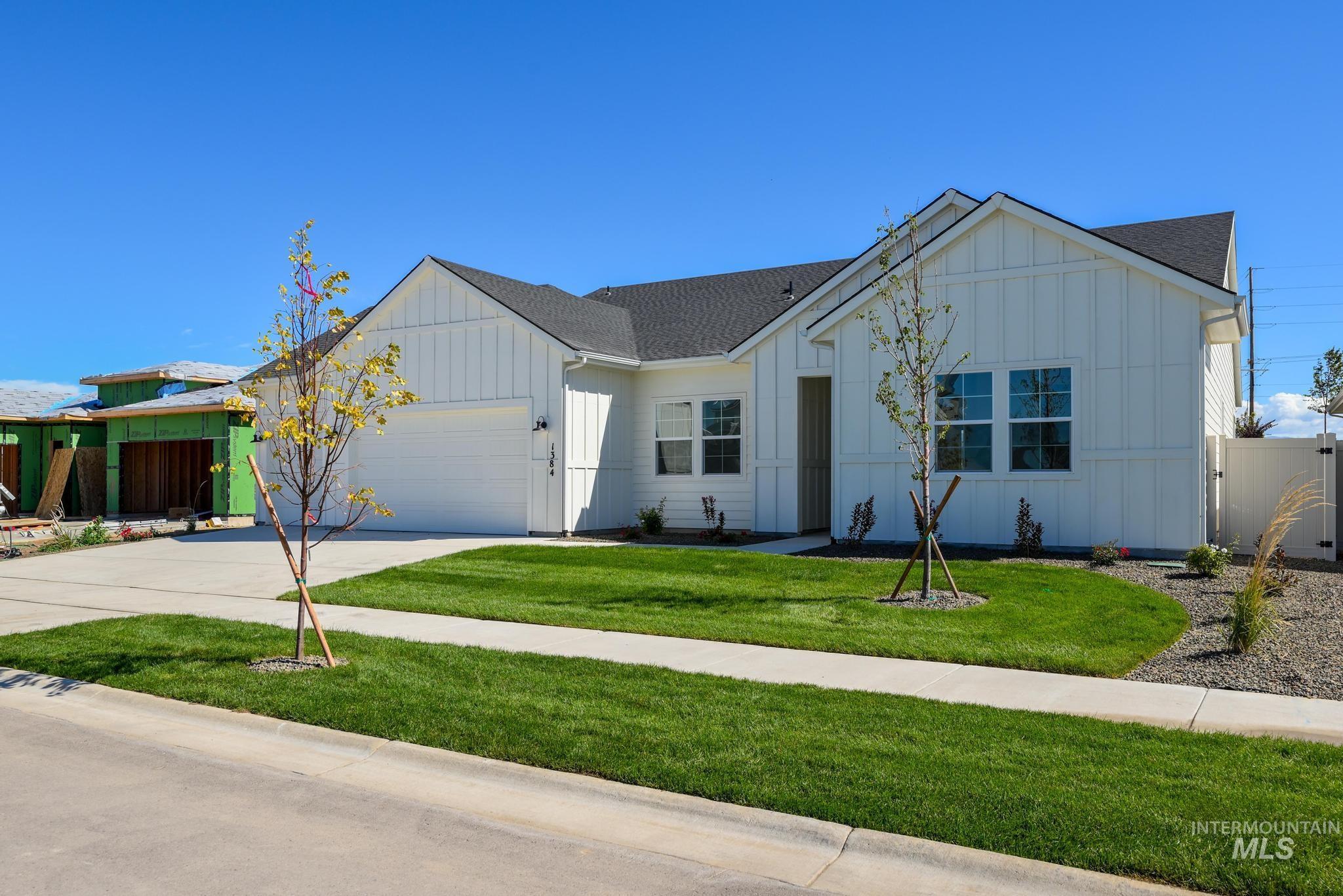 View of front of property featuring board and batten siding, a shingled roof, a garage, and driveway