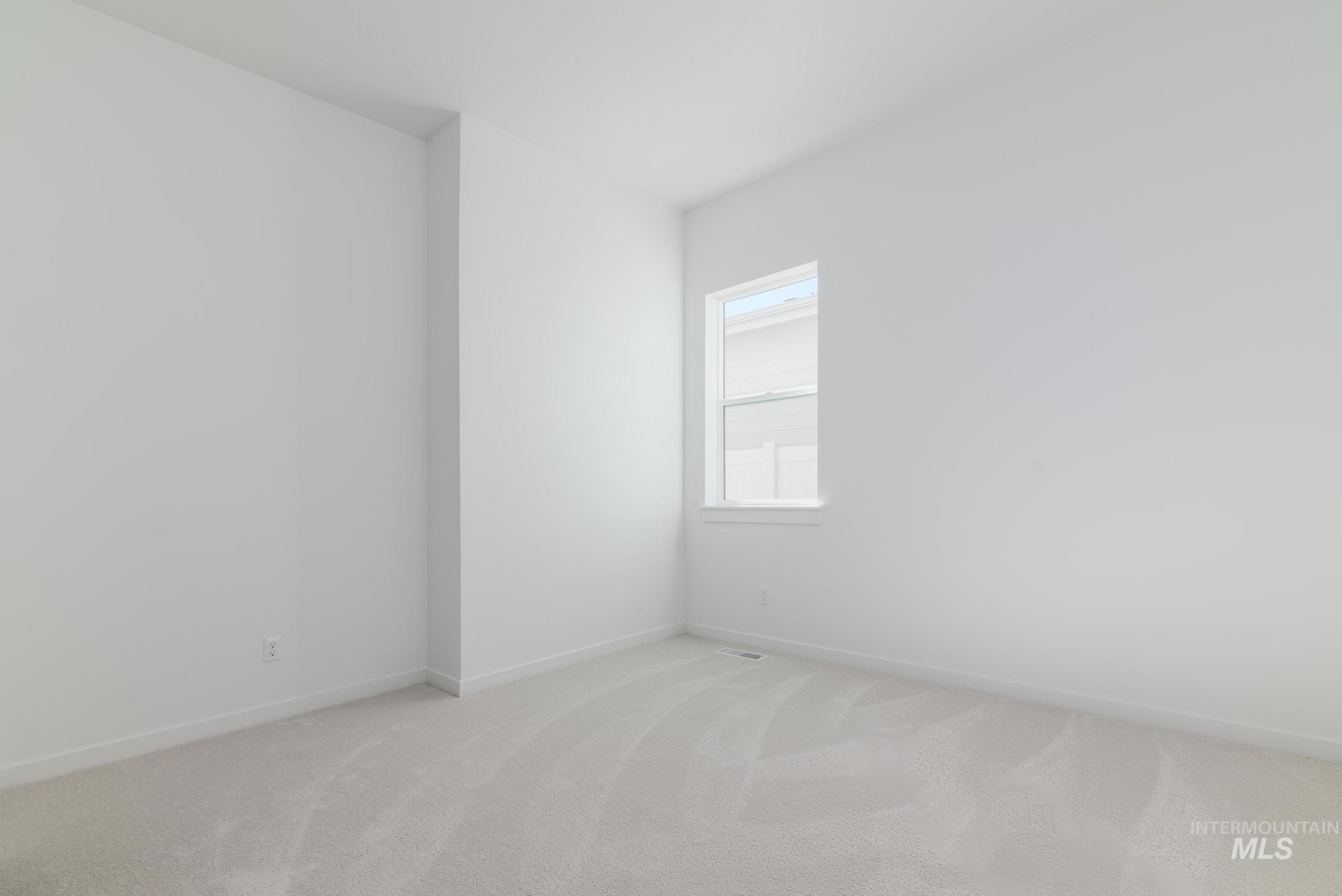 Spare room with light colored carpet and baseboards
