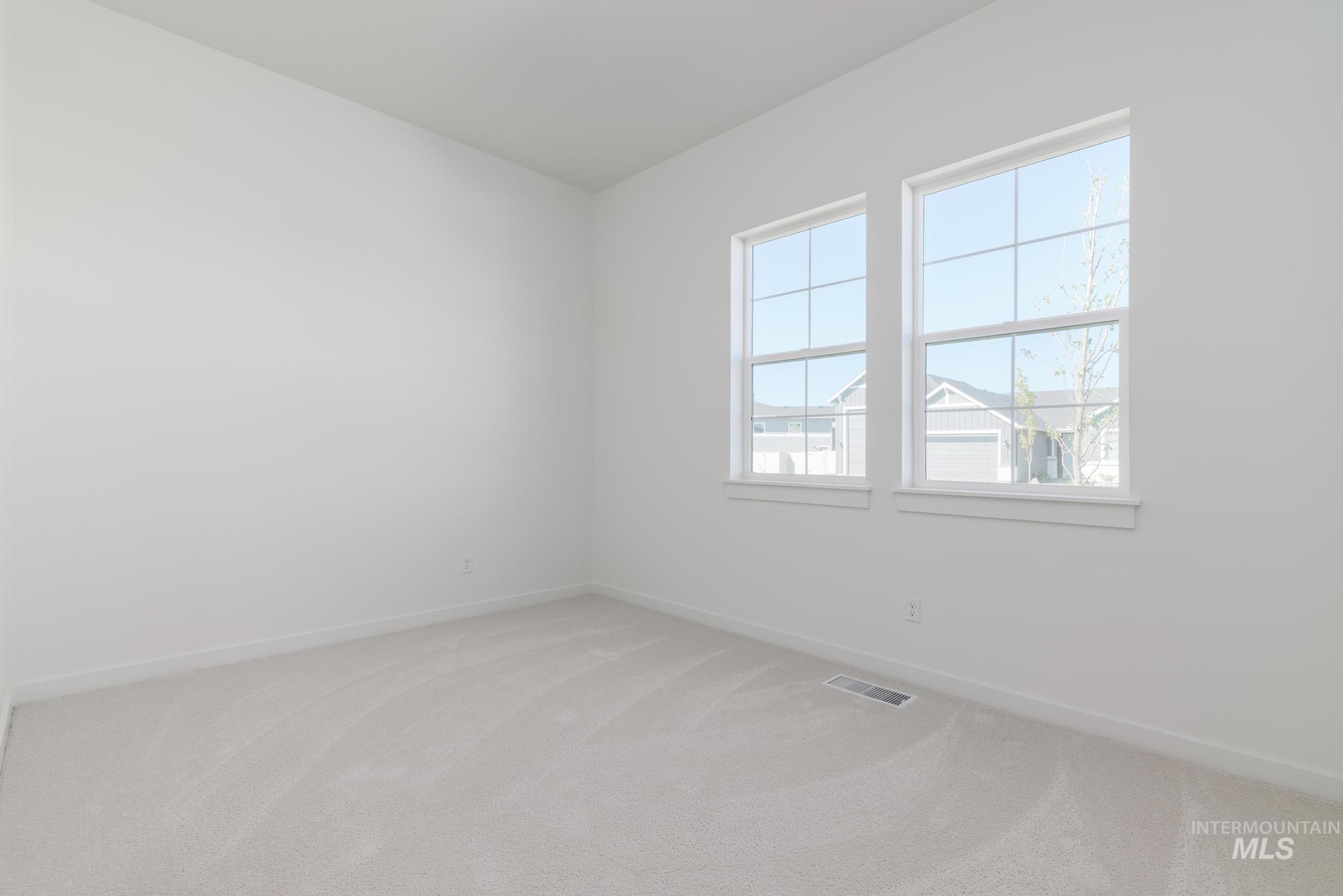 Empty room featuring light colored carpet and baseboards