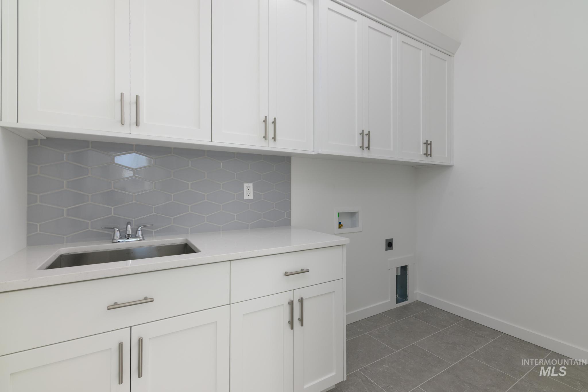 Laundry room with light tile patterned flooring, cabinet space, hookup for a washing machine, and electric dryer hookup