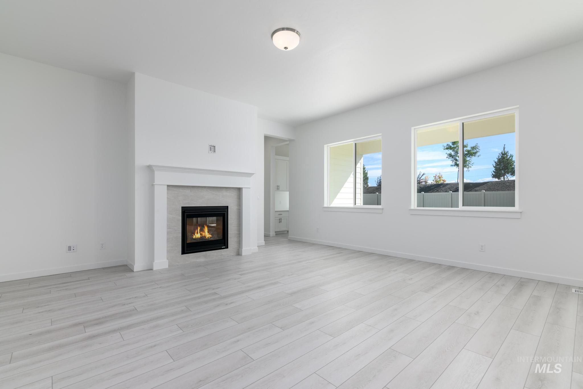 Unfurnished living room featuring a tile fireplace and light wood-style flooring