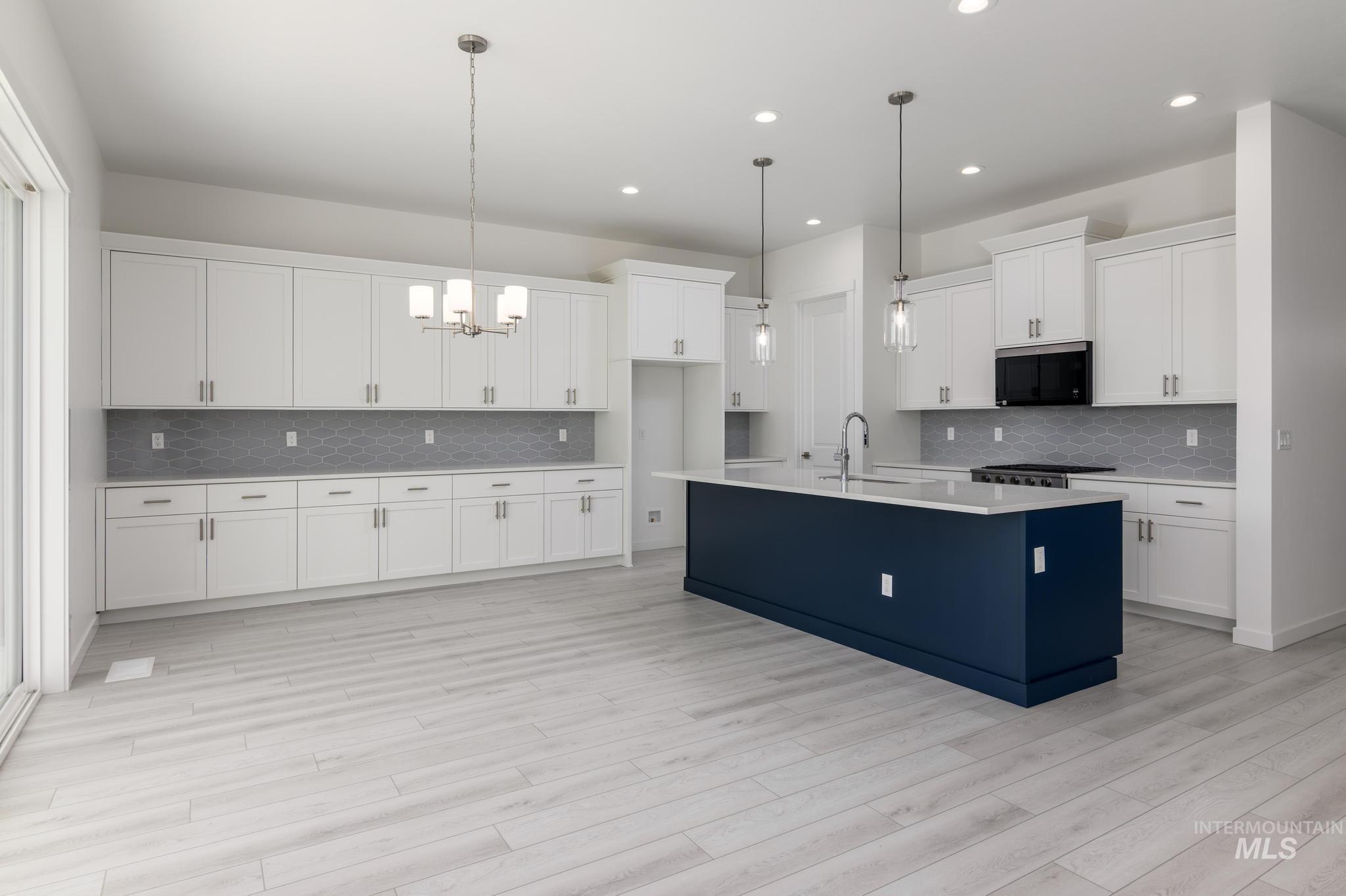 Kitchen featuring hanging light fixtures, decorative backsplash, white cabinets, a chandelier, and recessed lighting