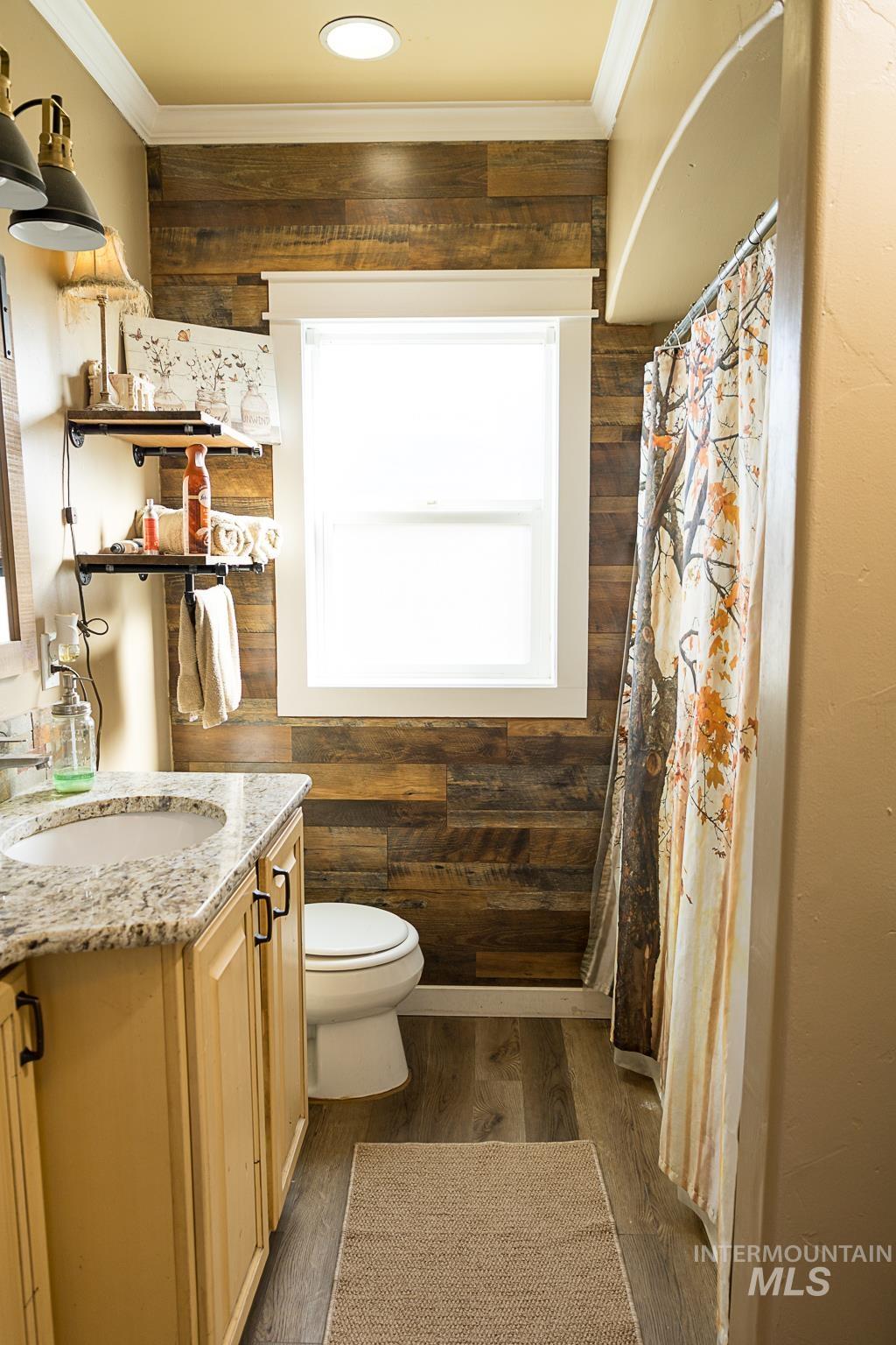 Bathroom featuring vanity, dark wood-style flooring, wooden walls, ornamental molding, and curtained shower
