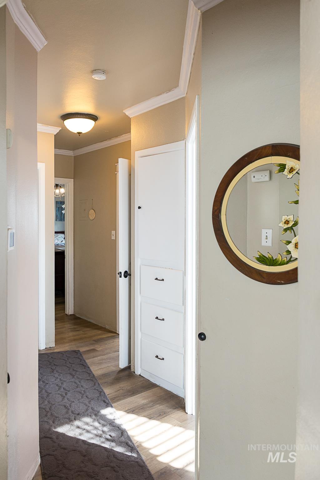 Hallway with ornamental molding and light wood finished floors