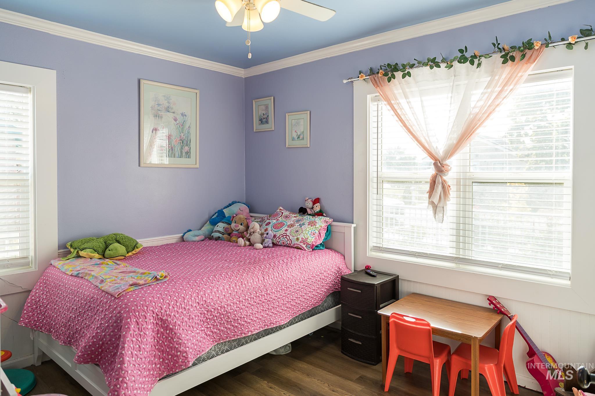 Bedroom with ornamental molding, dark wood finished floors, and a ceiling fan