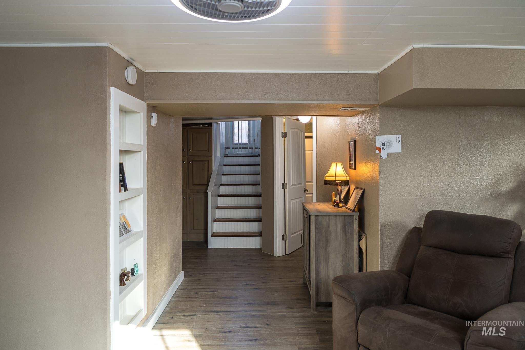 Hall featuring stairs, wood finished floors, a textured wall, ornamental molding, and built in shelves