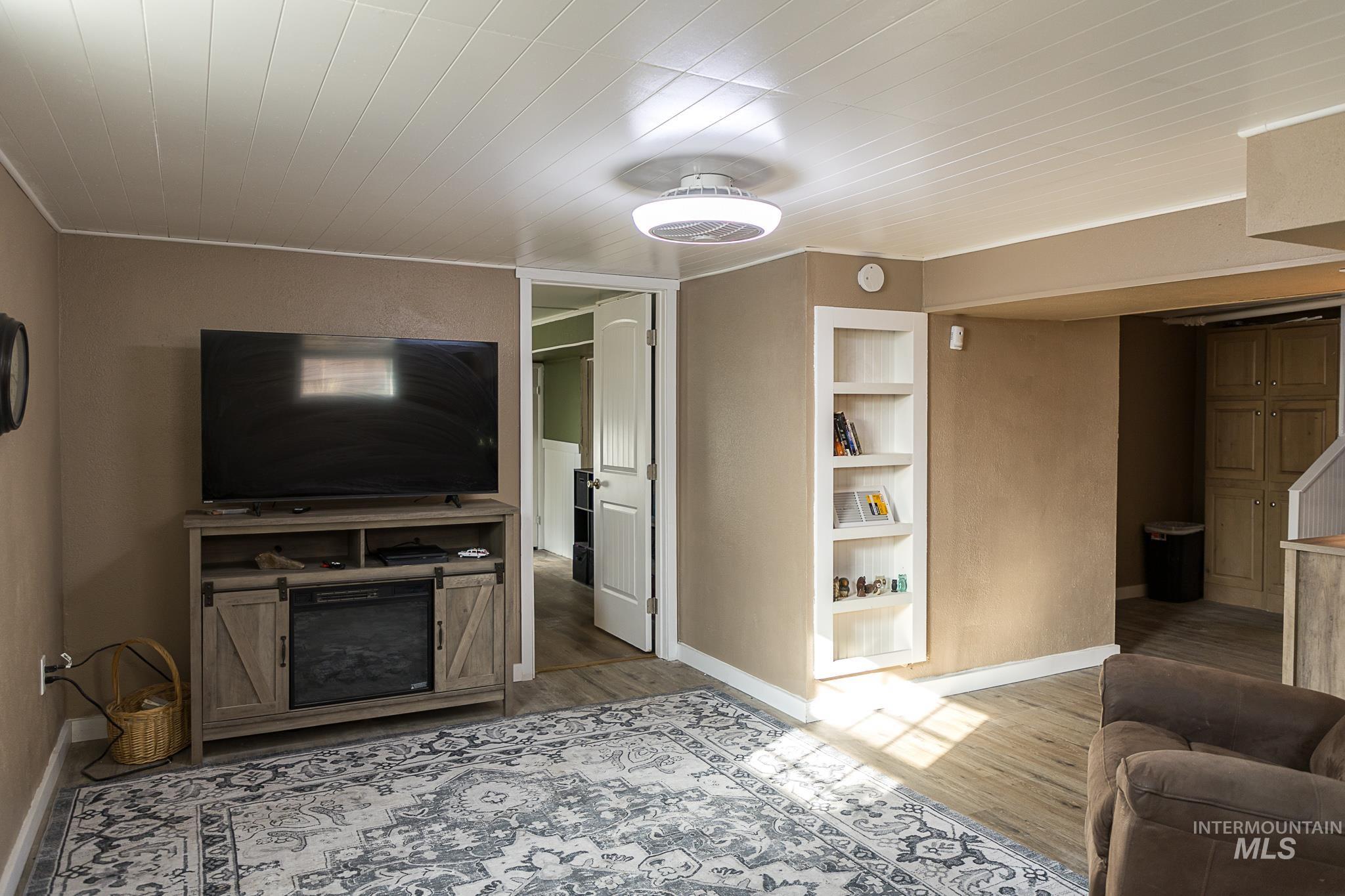 Living area featuring light wood-style floors, built in shelves, and ornamental molding