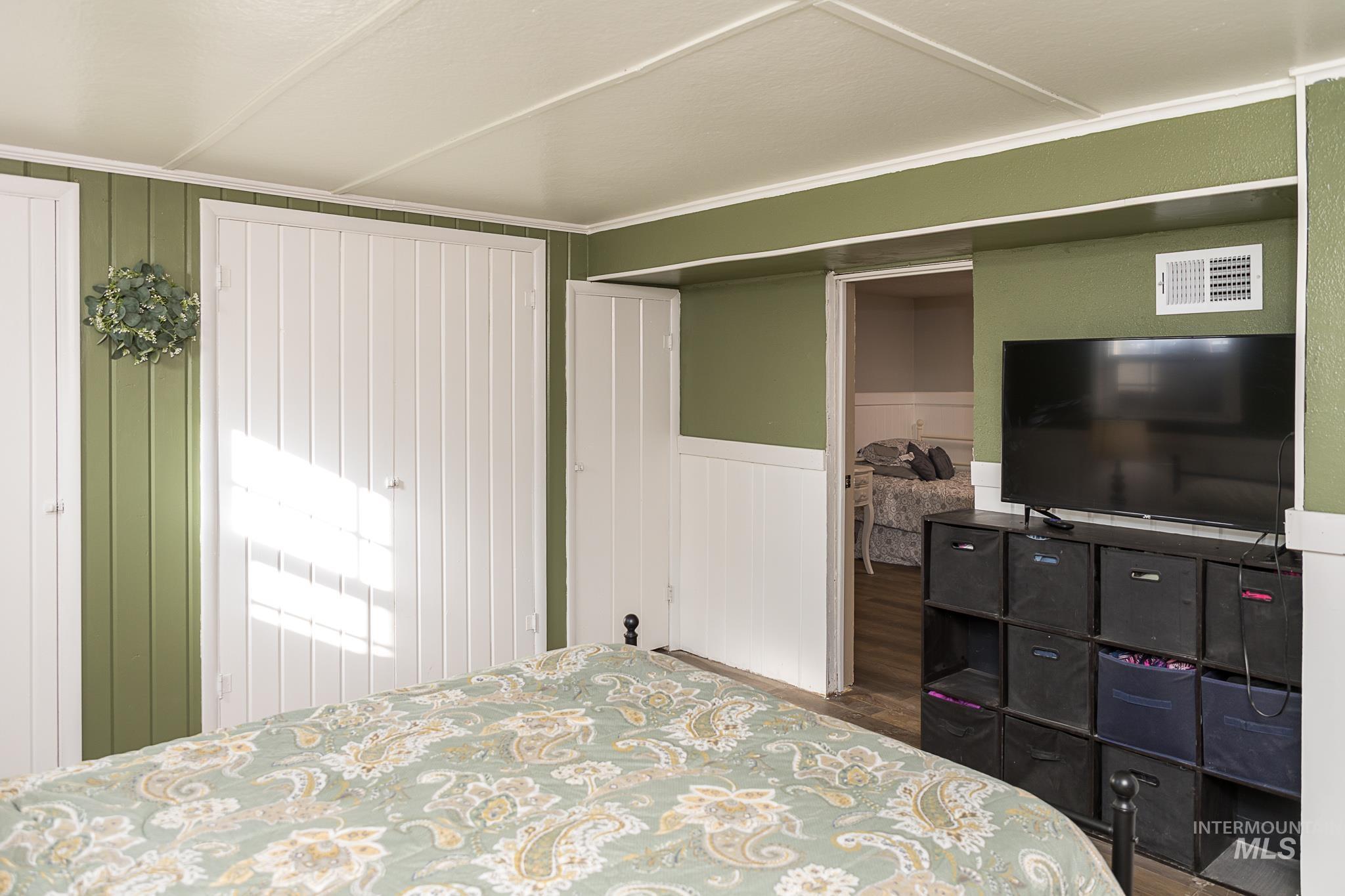 Bedroom featuring wood finished floors and a wainscoted wall