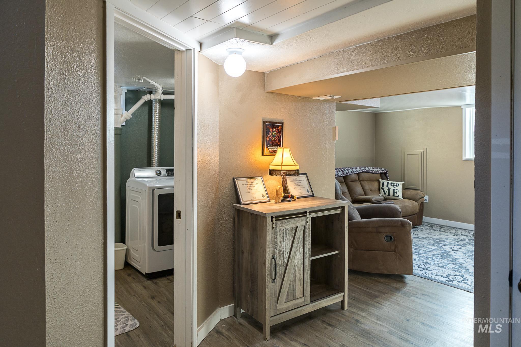 Hall with a textured wall, washer / clothes dryer, and wood finished floors