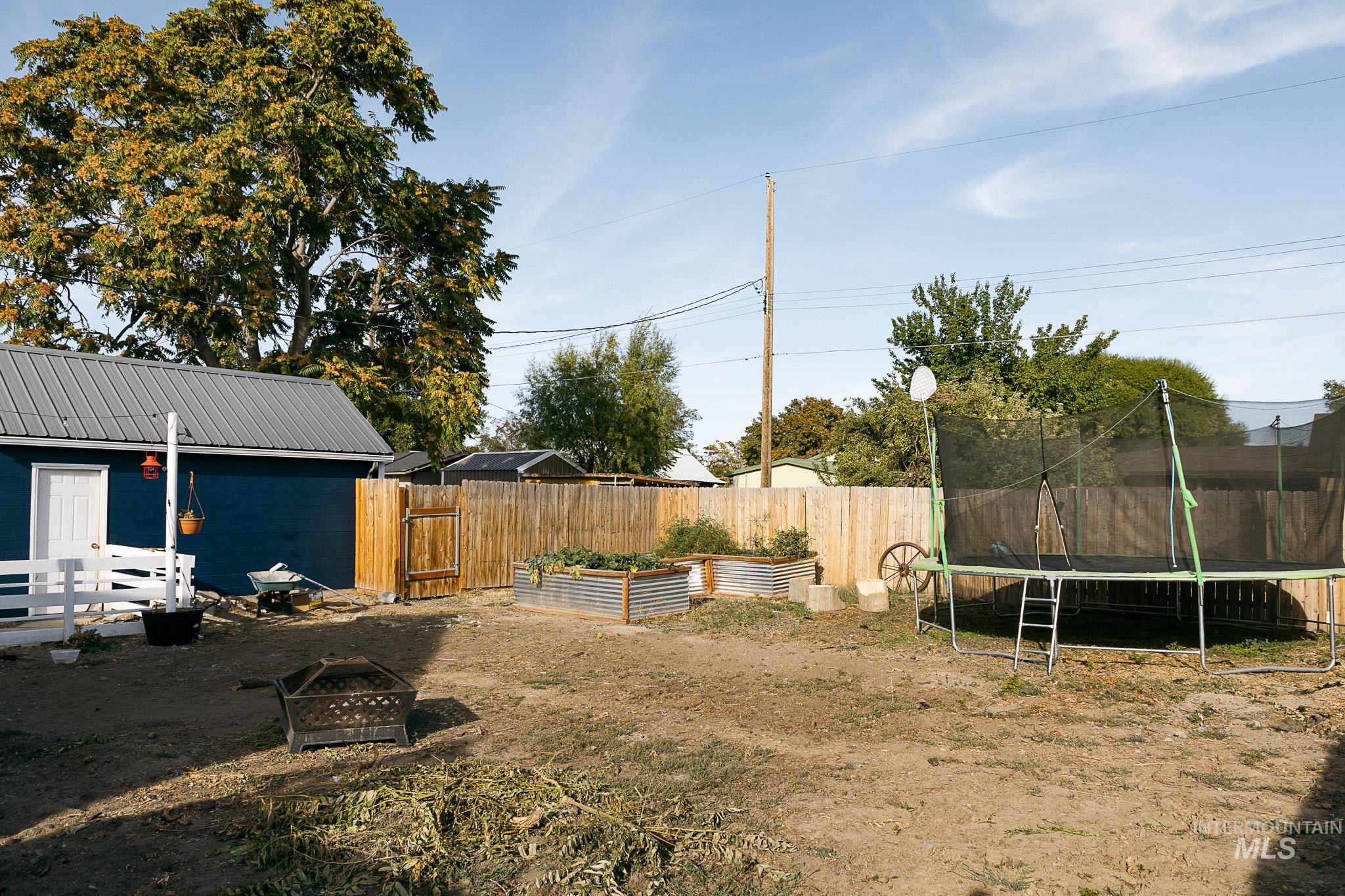 Fenced backyard with a vegetable garden and a trampoline