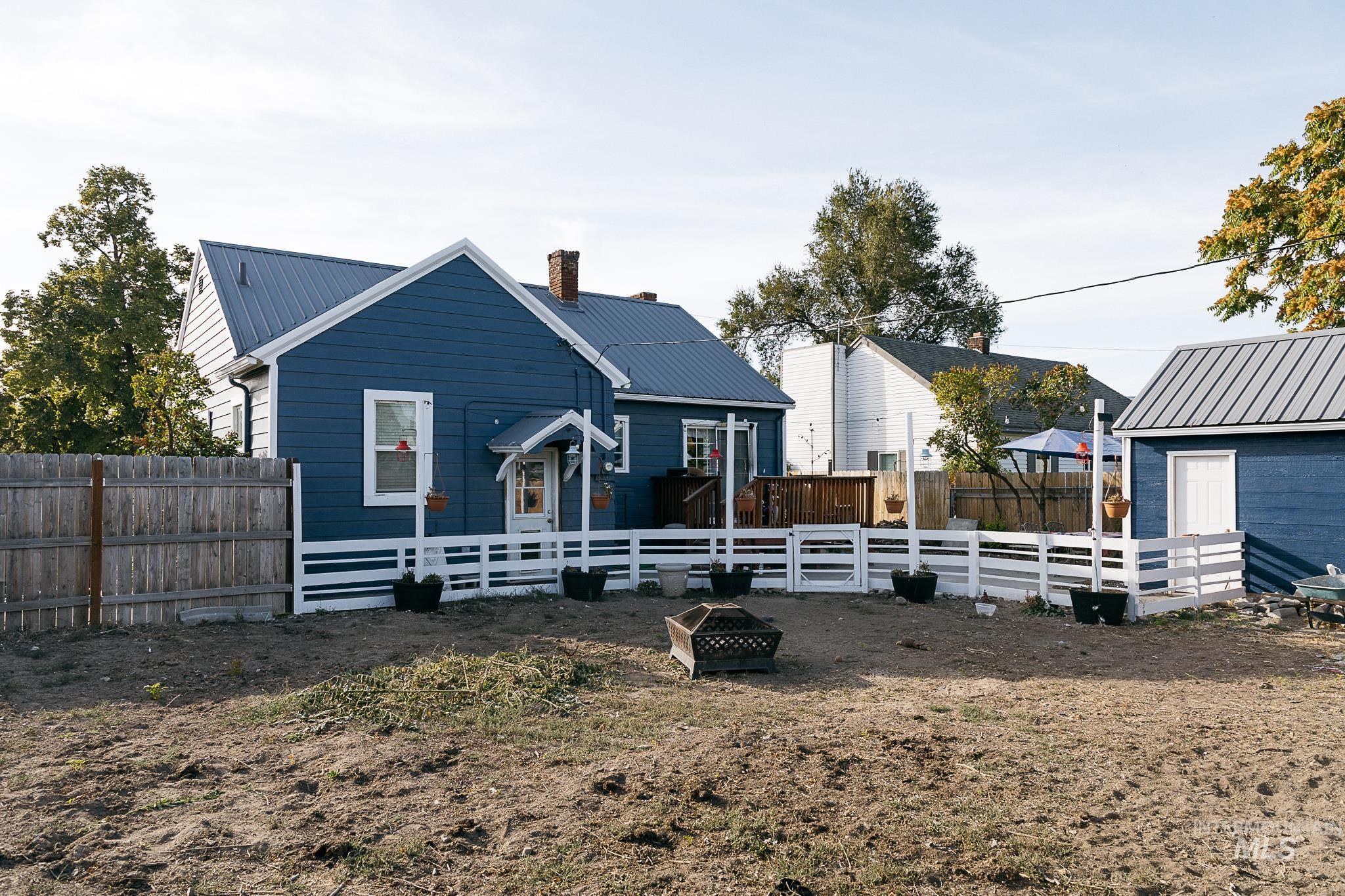 View of front facade featuring a metal roof, a fenced backyard, and a chimney