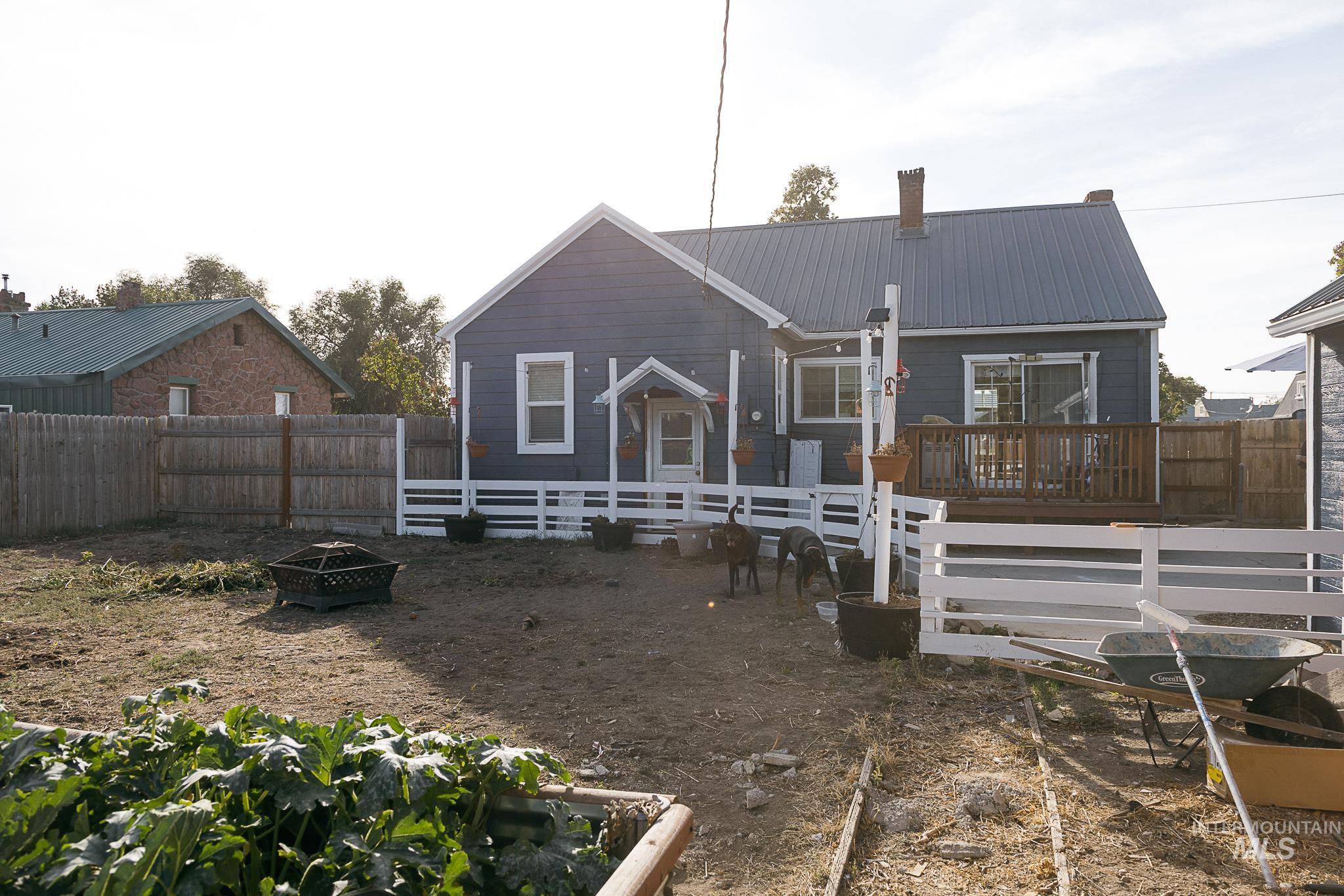 Rear view of property with an outdoor fire pit, a fenced backyard, a metal roof, and a wooden deck