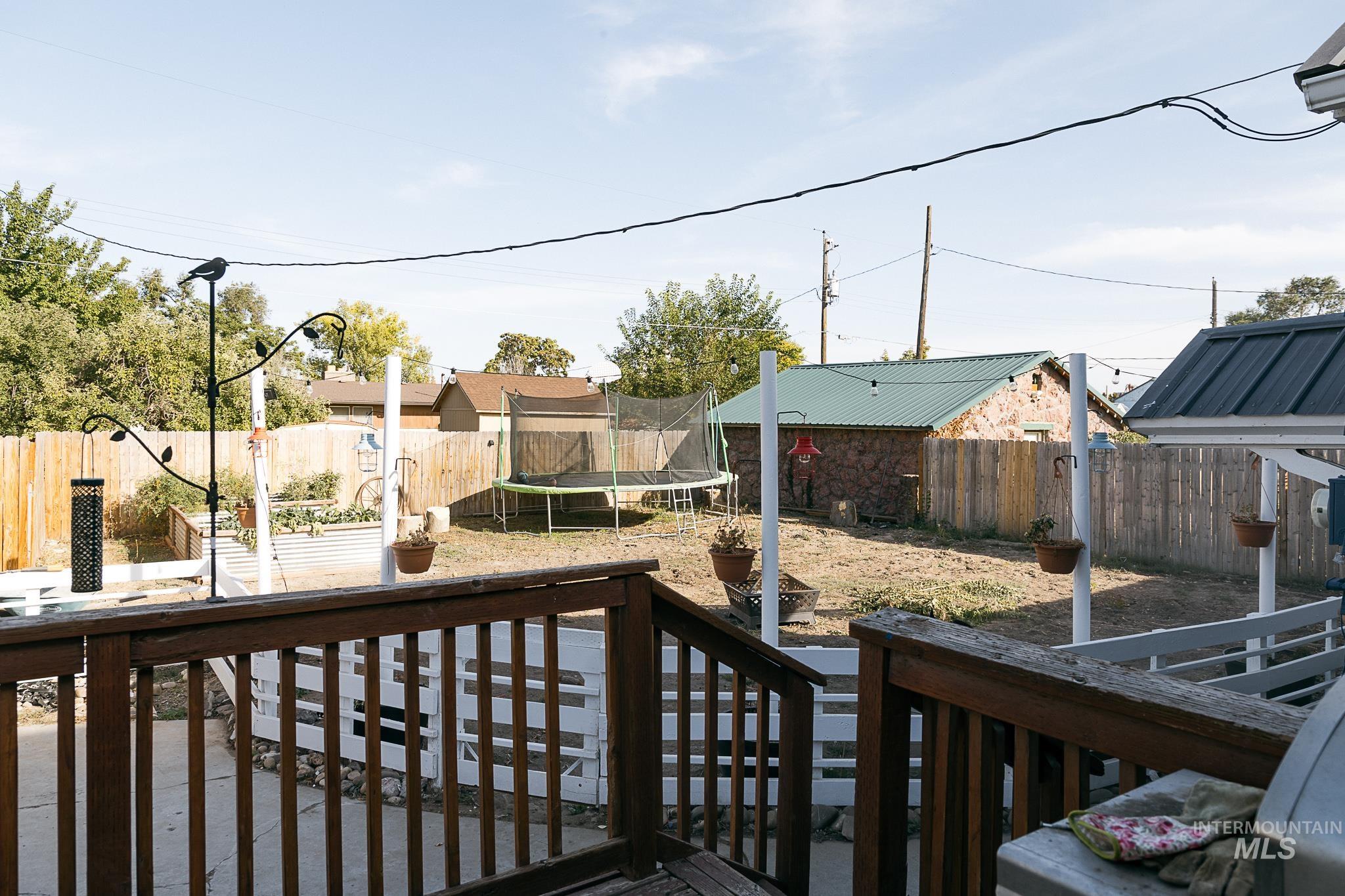 Wooden deck with a trampoline and a fenced backyard