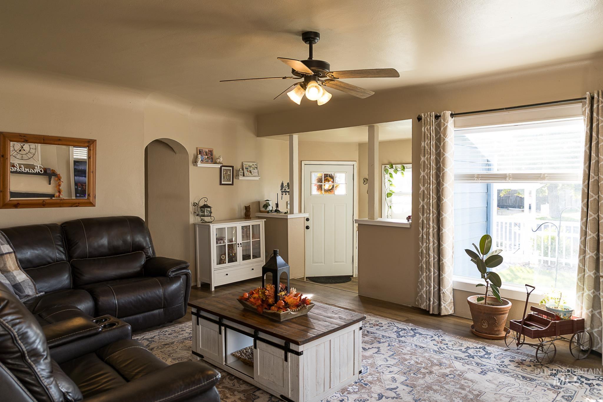 Living area with arched walkways, wood finished floors, and a ceiling fan