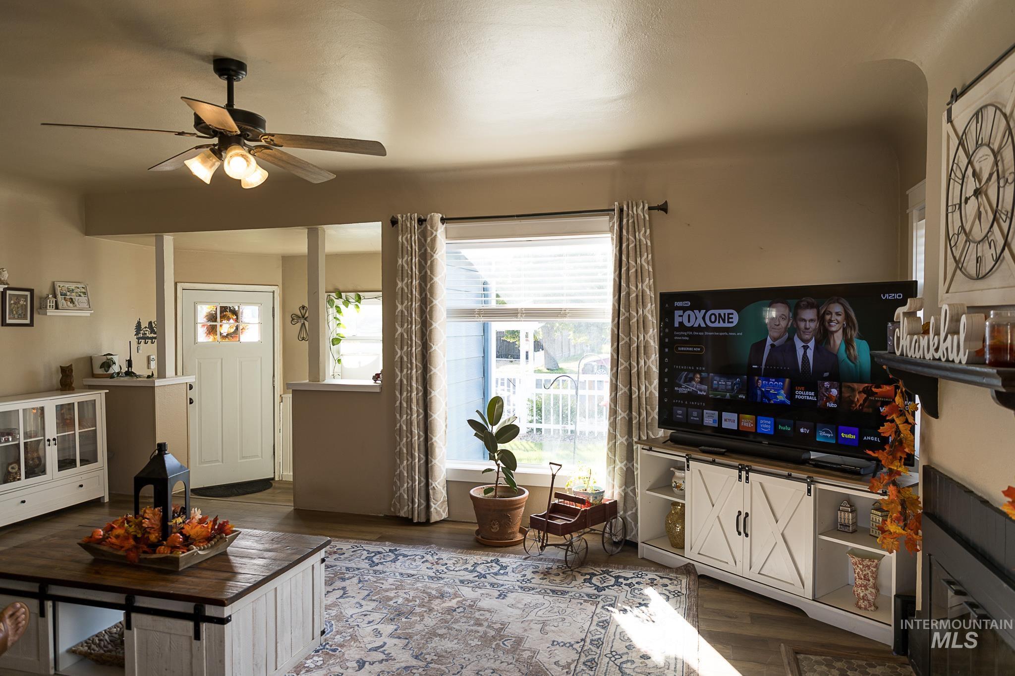 Living room featuring dark wood-style flooring and ceiling fan