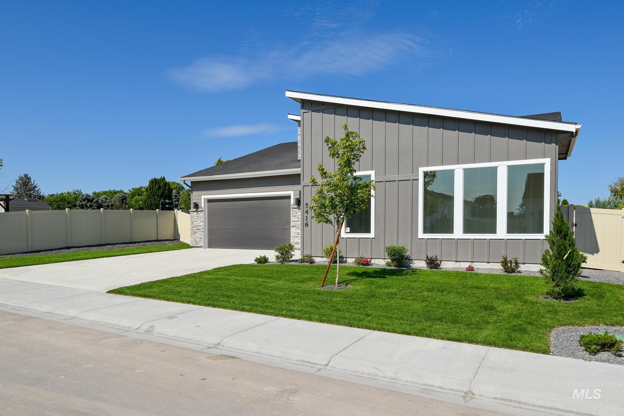 View of front of property with board and batten siding, driveway, and an attached garage