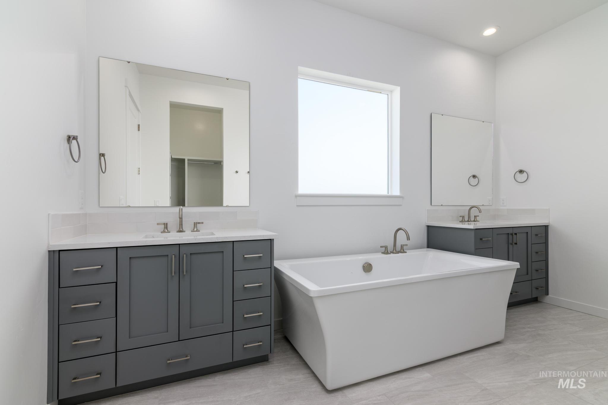 Full bath with a soaking tub, two vanities, a closet, and recessed lighting