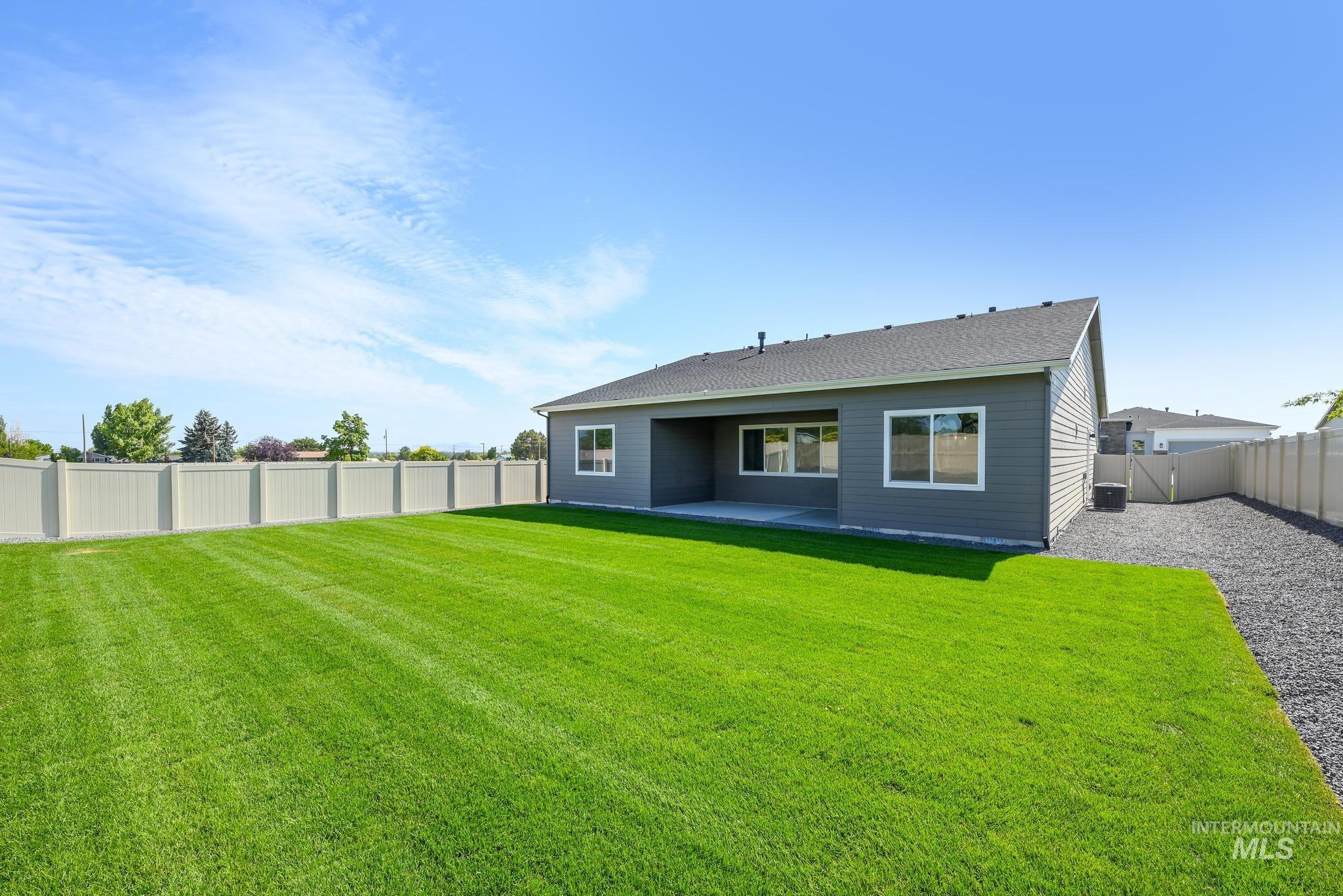 Rear view of house featuring a patio, a fenced backyard, and roof with shingles