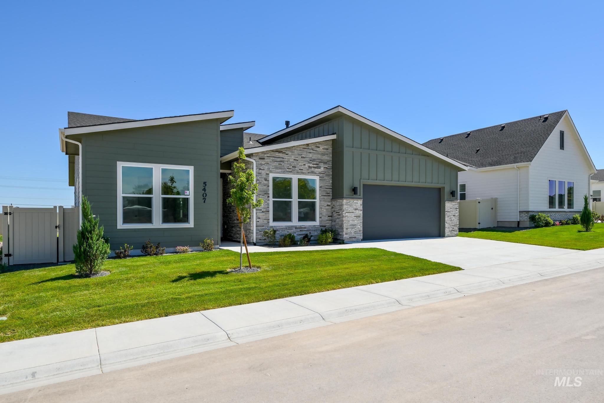 View of front of home featuring a gate, board and batten siding, a garage, concrete driveway, and stone siding