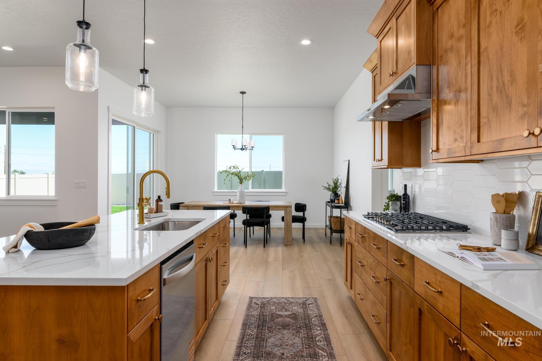 Kitchen featuring brown cabinets, light stone countertops, hanging light fixtures, backsplash, and recessed lighting