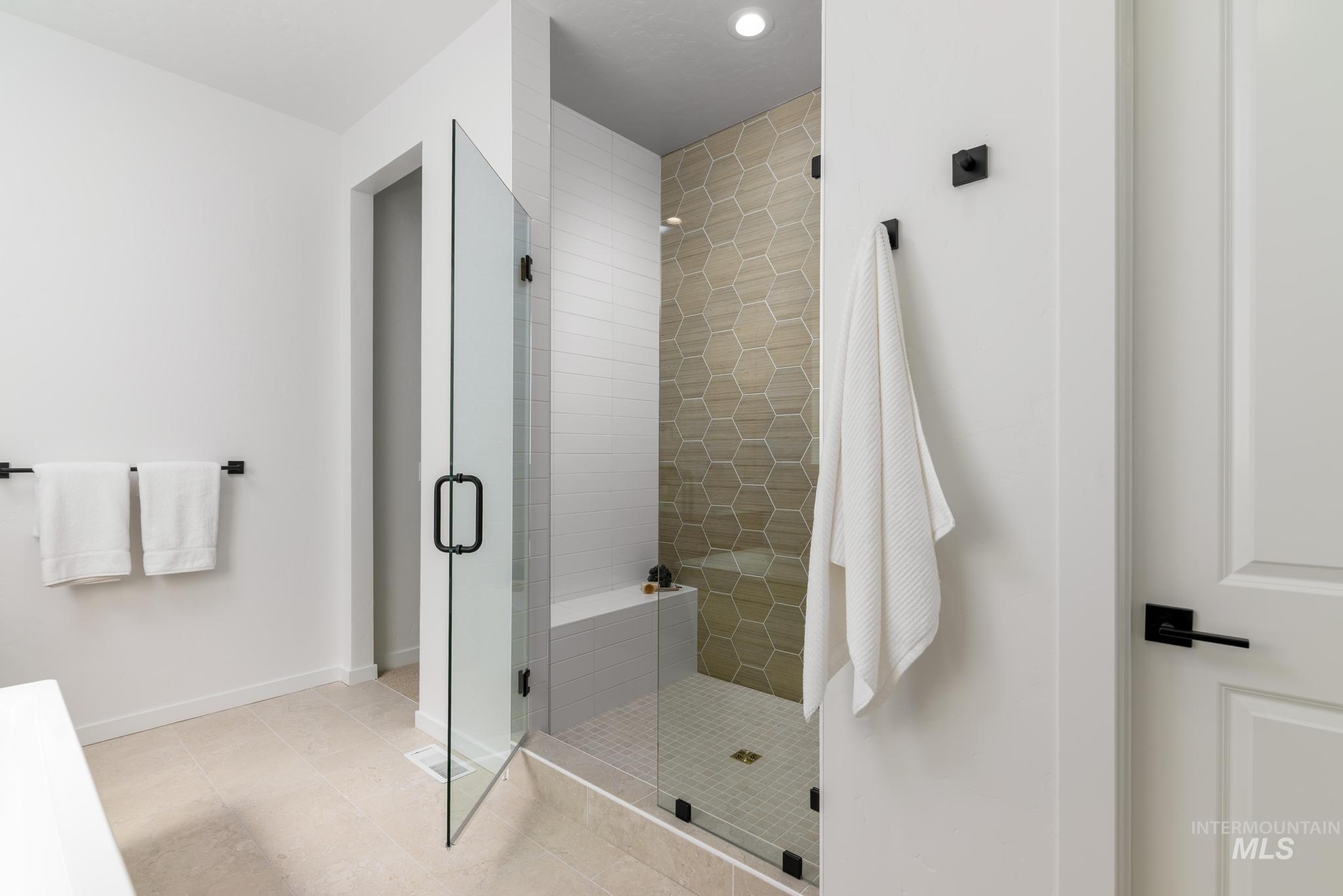 Full bath featuring a shower stall and light tile patterned flooring
