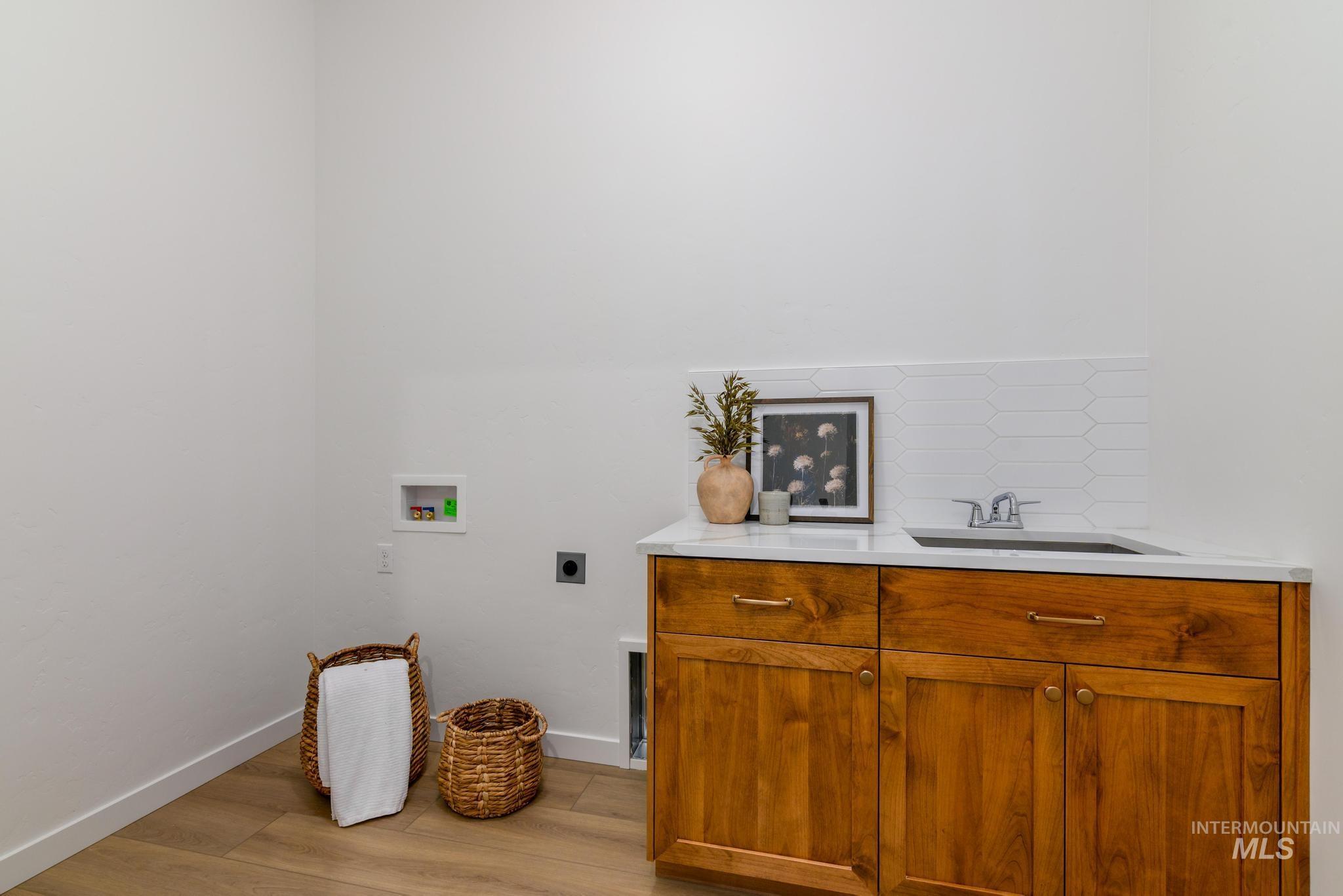 Washroom featuring hookup for an electric dryer, washer hookup, light wood-style flooring, and cabinet space