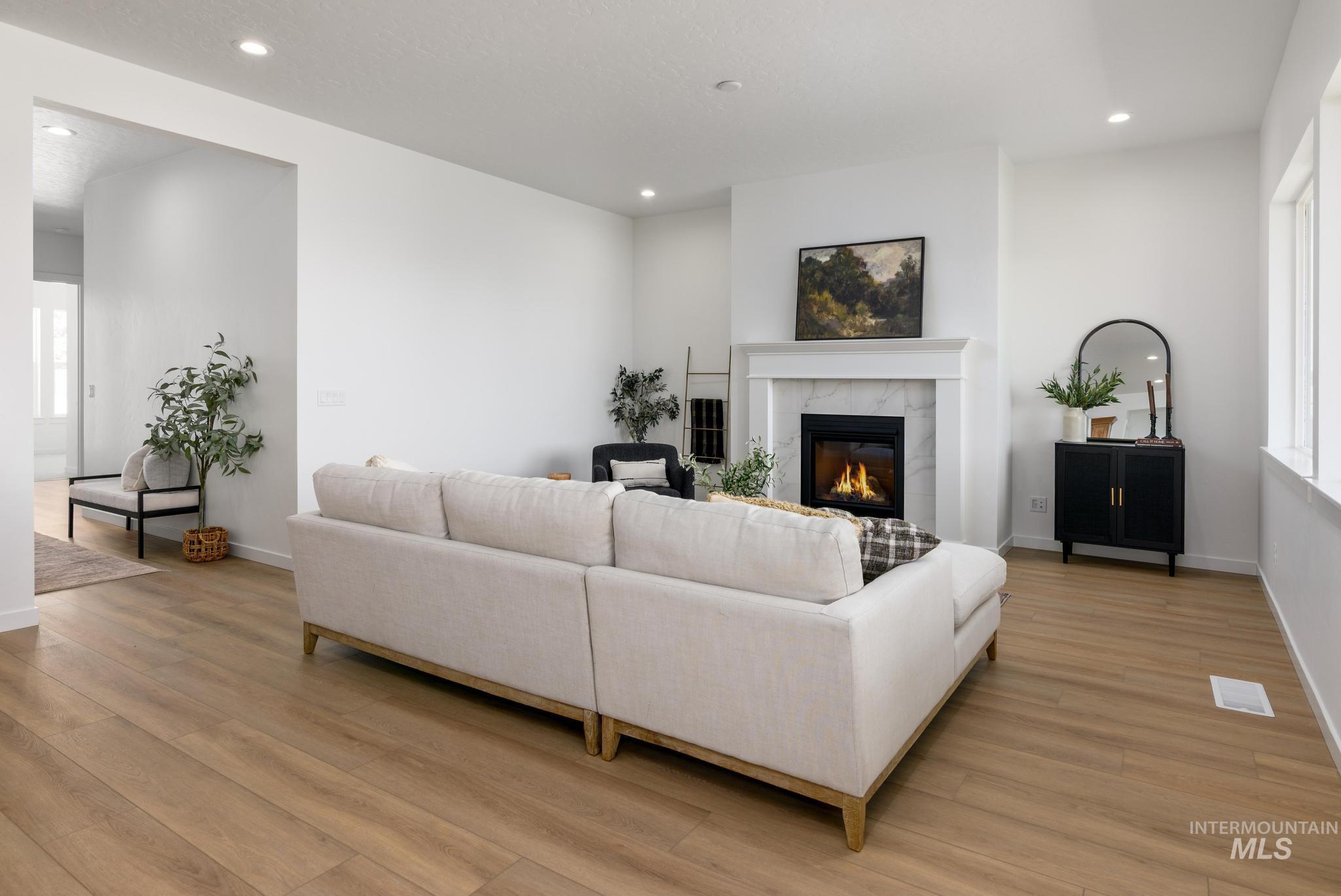Living area with recessed lighting, a tiled fireplace, and light wood-type flooring