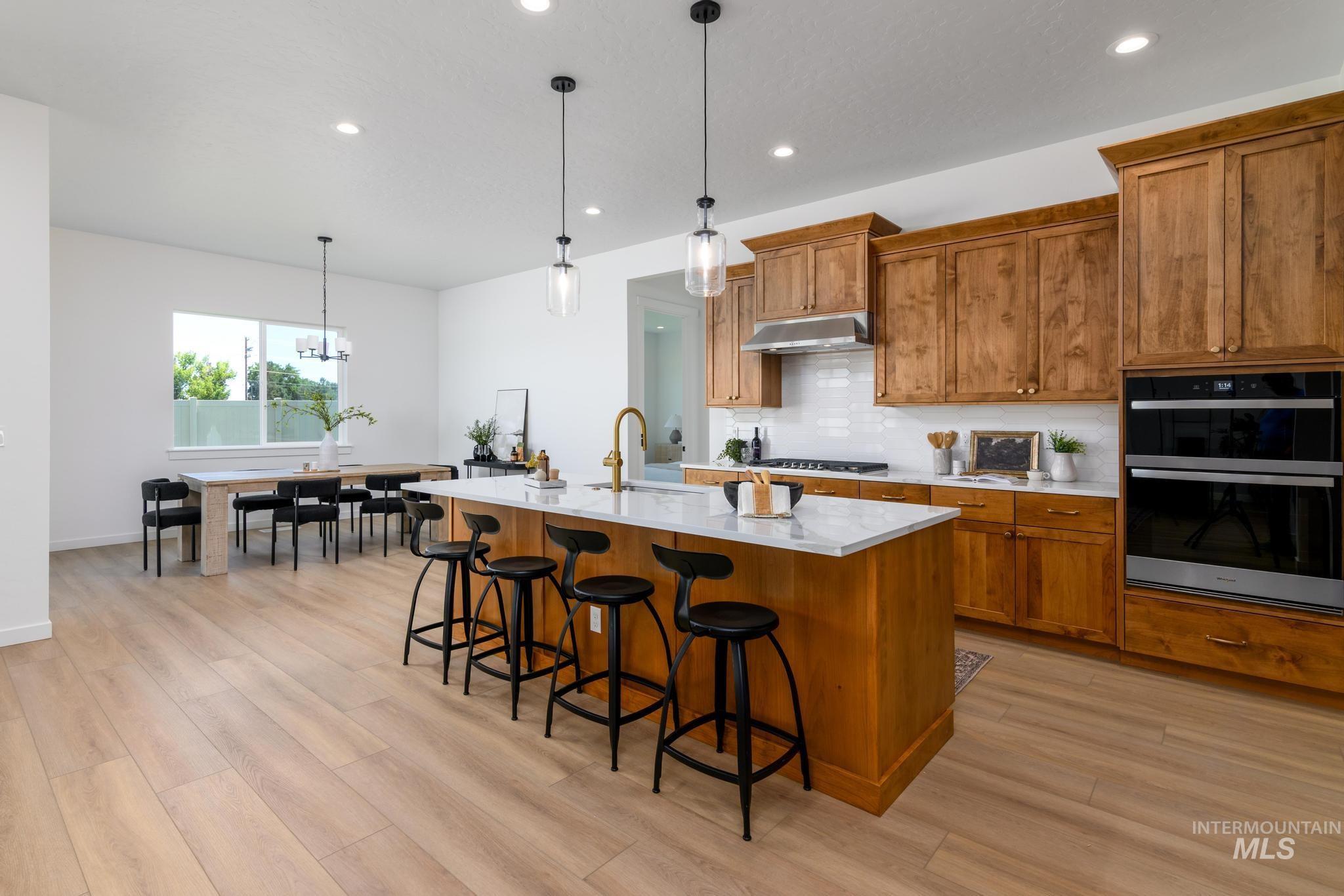 Kitchen featuring brown cabinetry, backsplash, decorative light fixtures, and recessed lighting