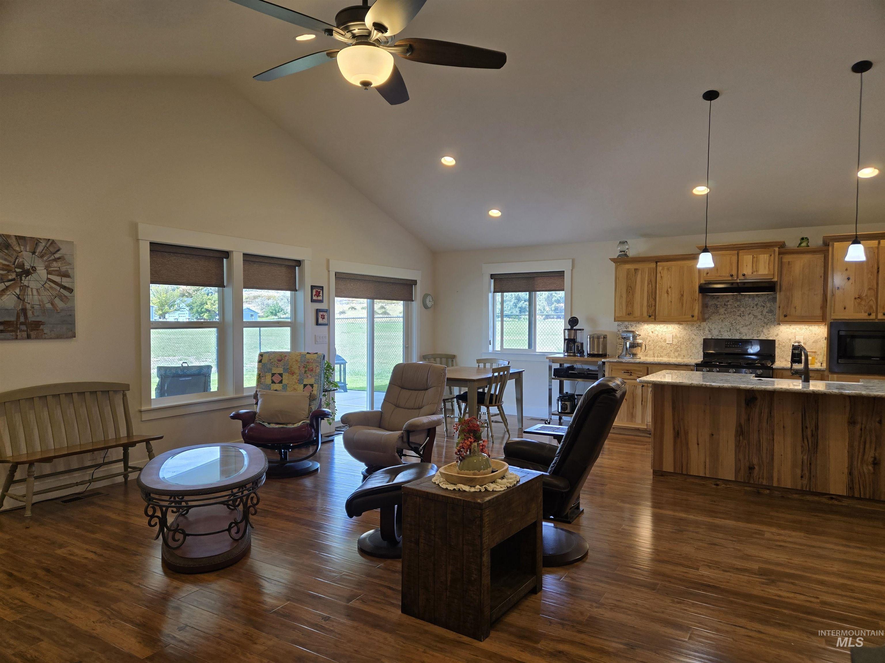 Living room with dark wood-style floors, a ceiling fan, recessed lighting, and high vaulted ceiling