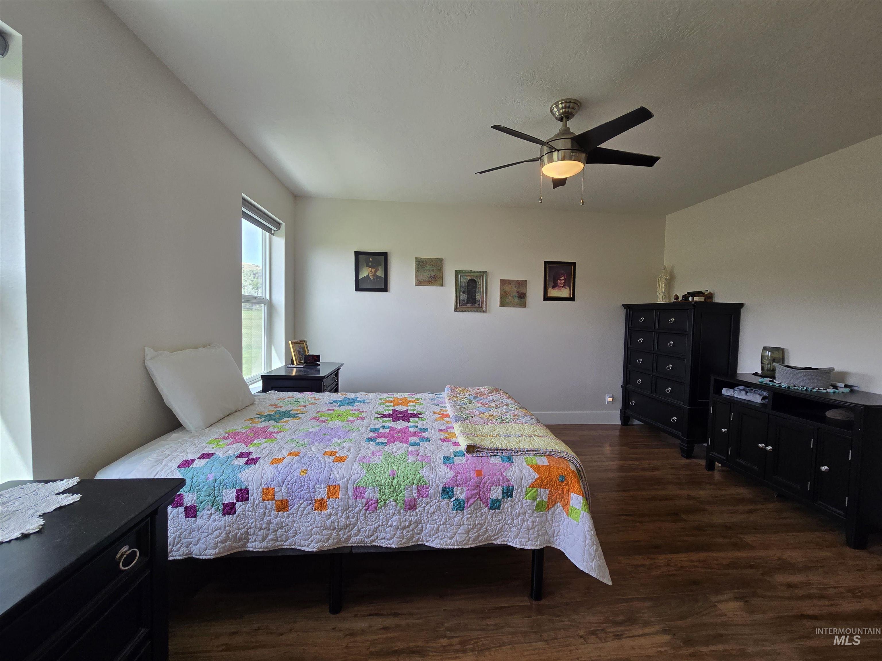 Bedroom with dark wood-style flooring and a ceiling fan