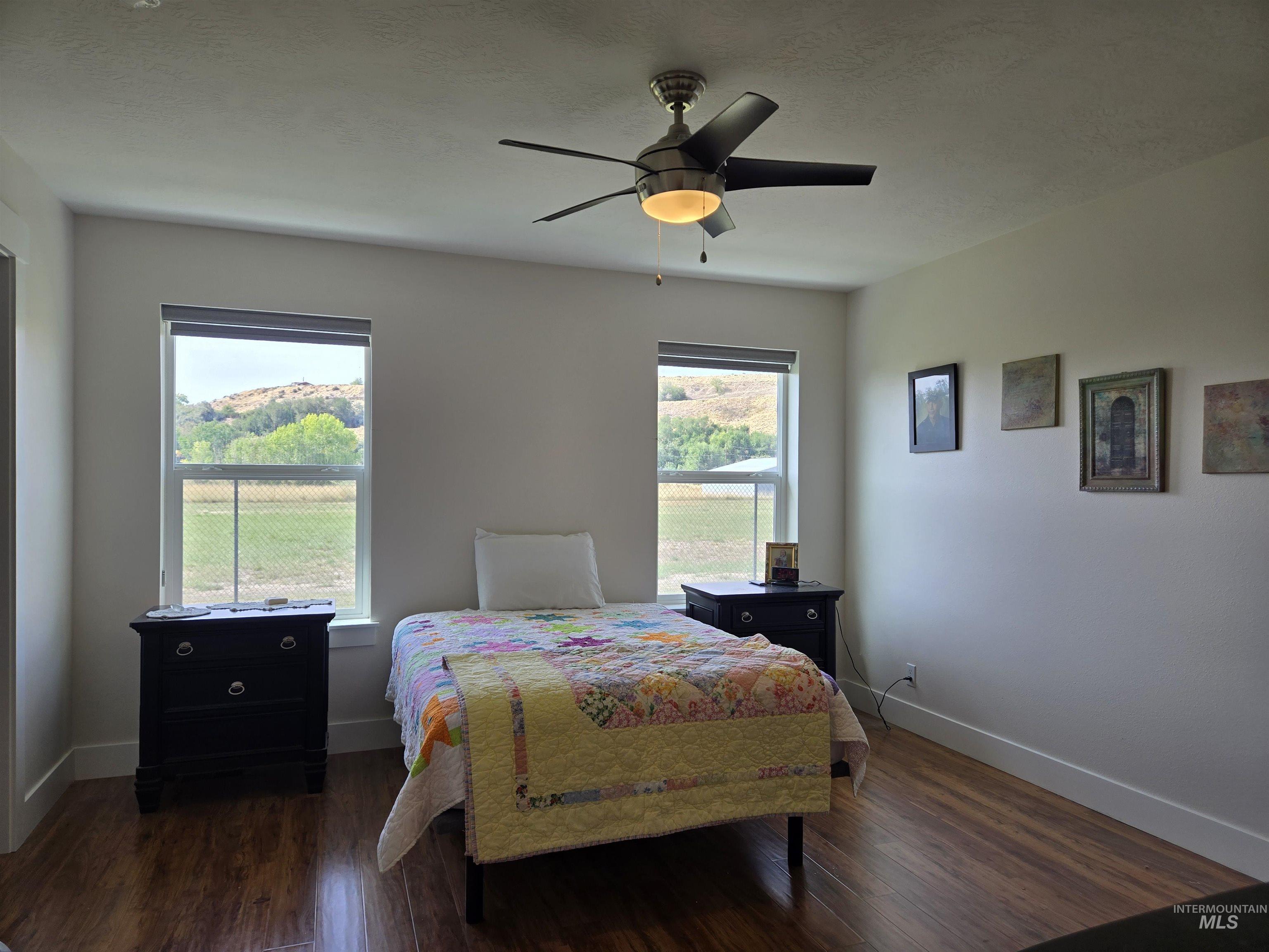 Bedroom with multiple windows, dark wood finished floors, and a ceiling fan