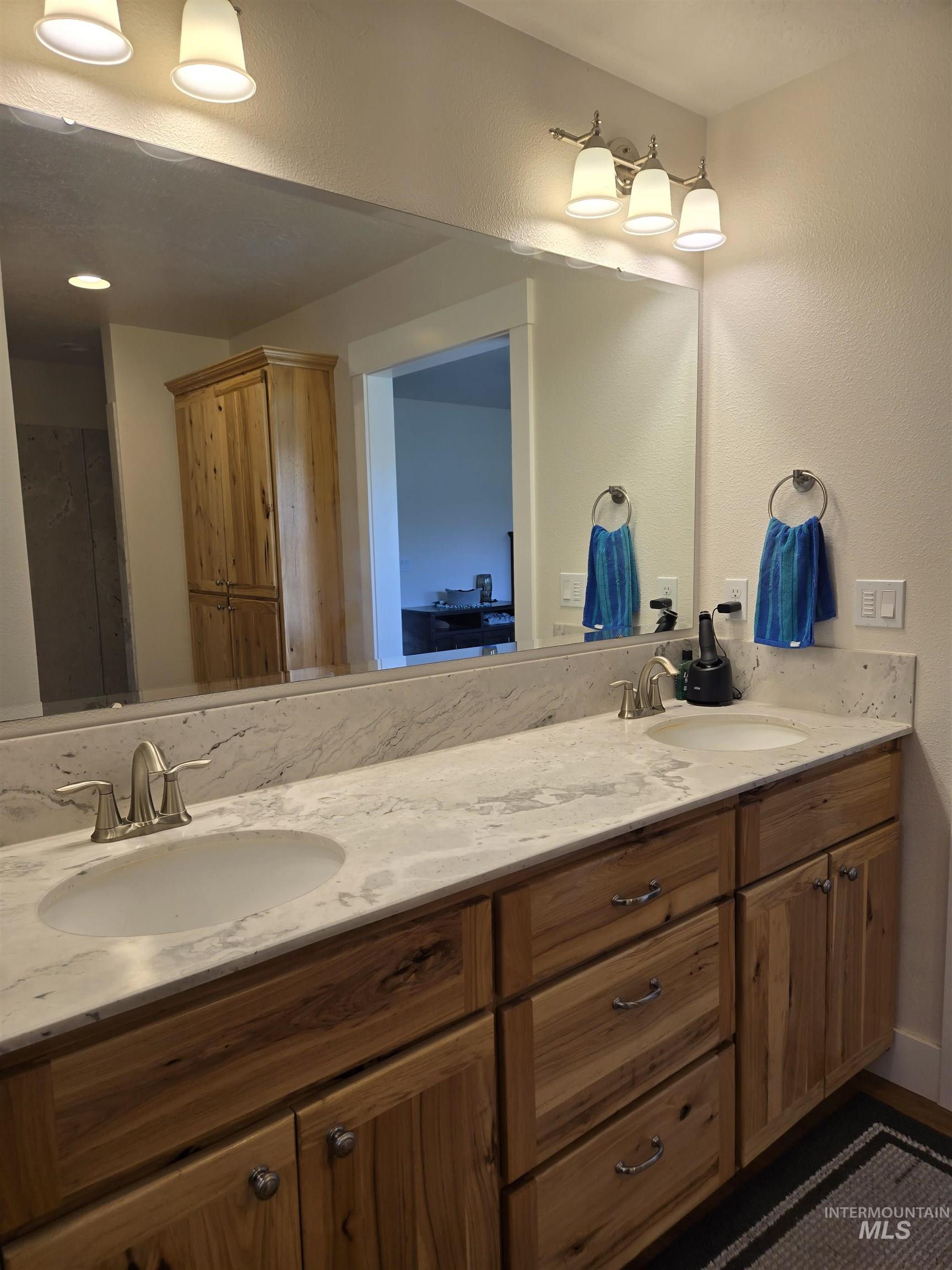 Bathroom featuring double vanity and a textured wall